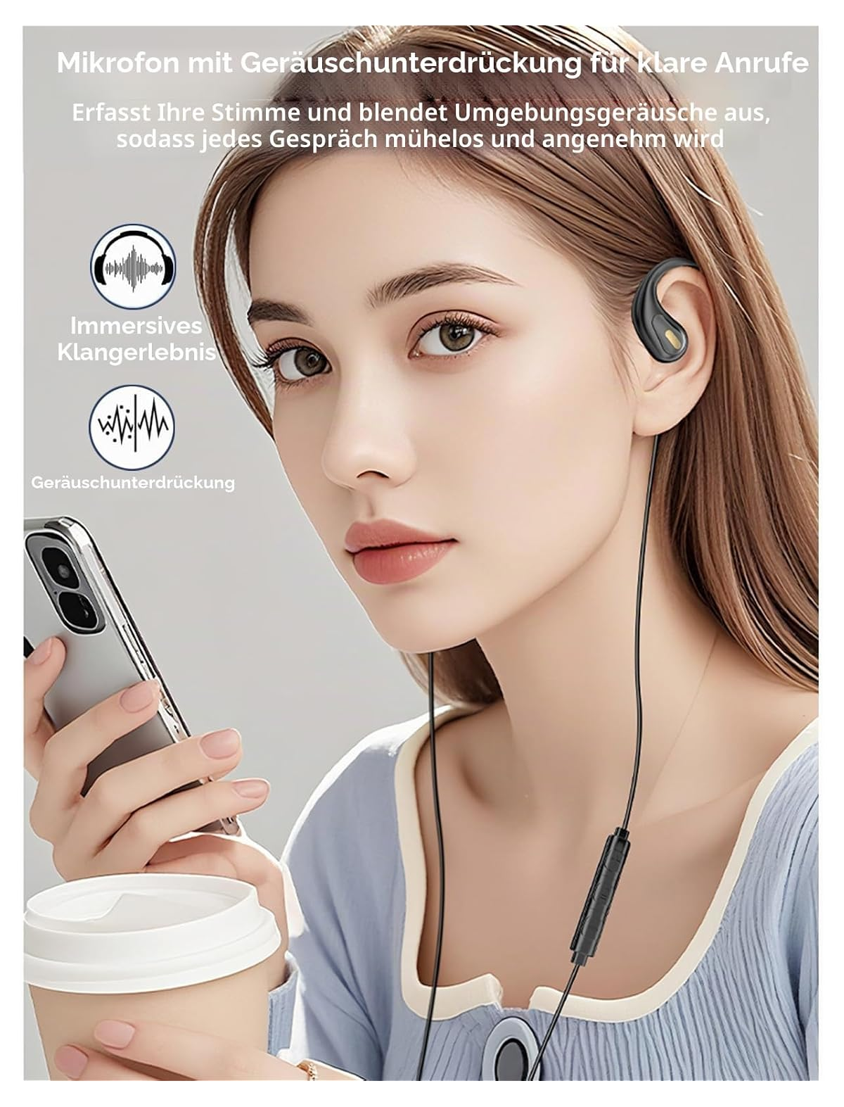 Eine Frau trägt ohrumschließende Kopfhörer mit Kabel und hält ein Smartphone sowie einen Kaffeebecher in den Händen.