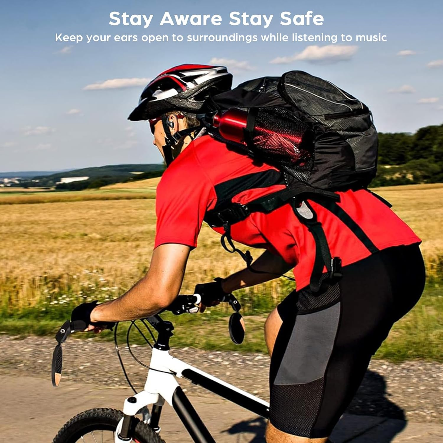 Radfahrer mit Helm und Rucksack fährt auf einer asphaltierten Straße an einem ländlichen Feld entlang.