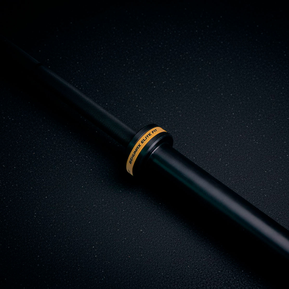 Una barra negra con un anillo amarillo y texto yace diagonalmente sobre una superficie oscura.