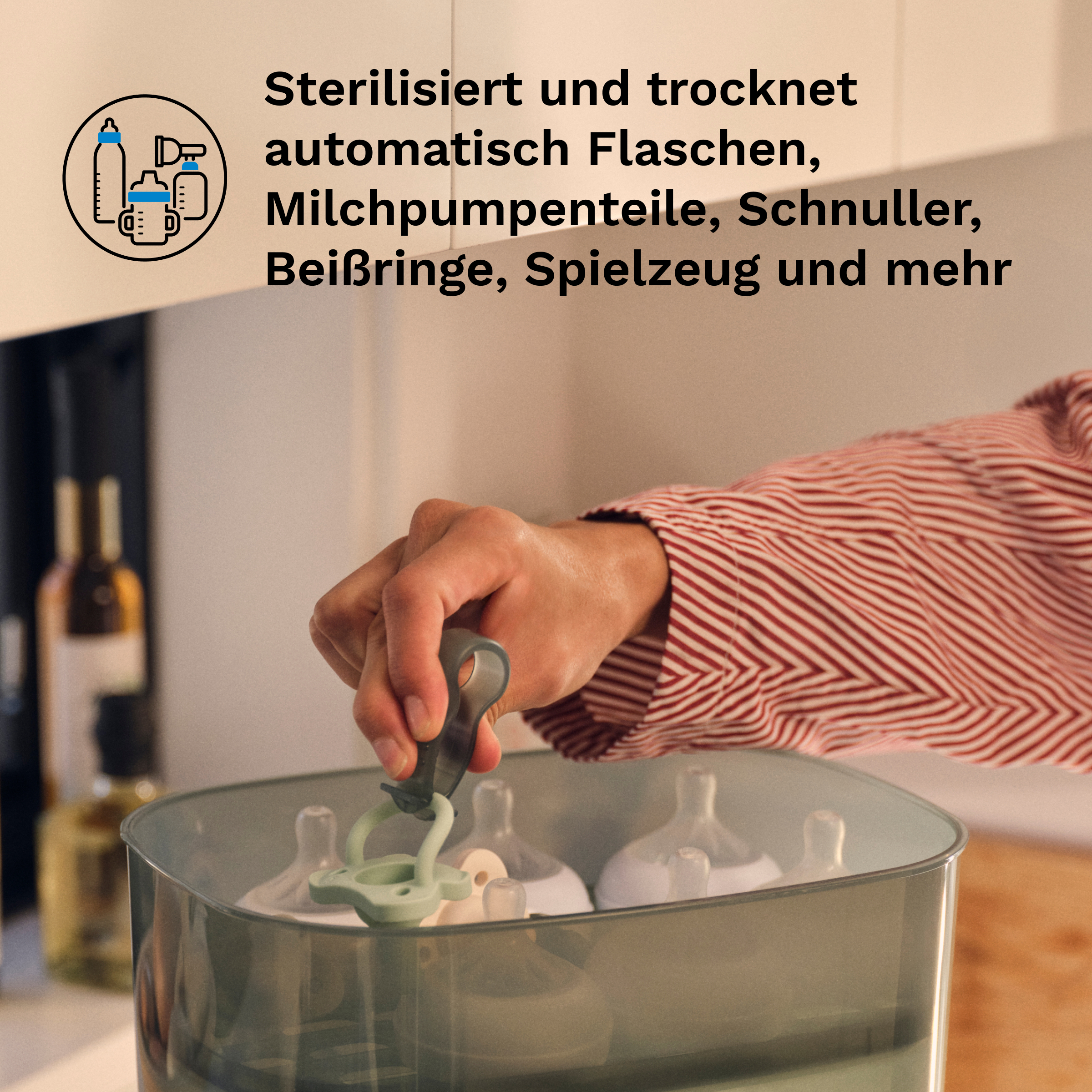 Hand in rot-weißem Hemd nimmt einen Schnuller aus einem elektrischen Babyflaschen-Sterilisator.