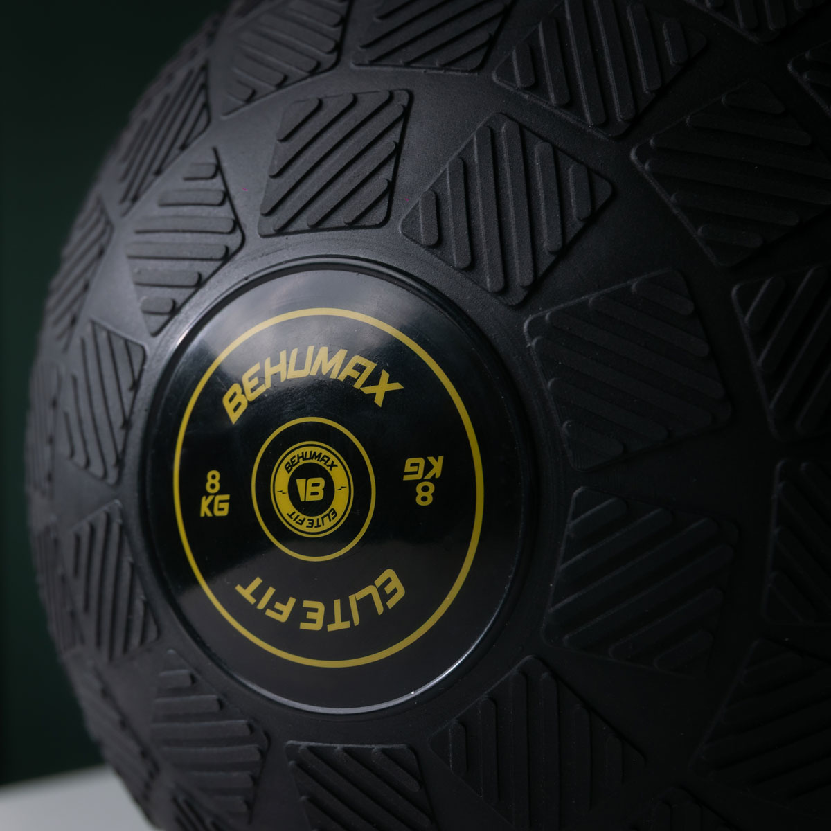 Primer plano de un balón medicinal negro texturizado de 8 kg Behumax Elite Fit con texto amarillo.
