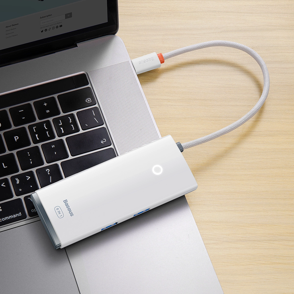 Un hub USB-C bianco Baseus 6 in 1 è collegato a un computer portatile argenteo.