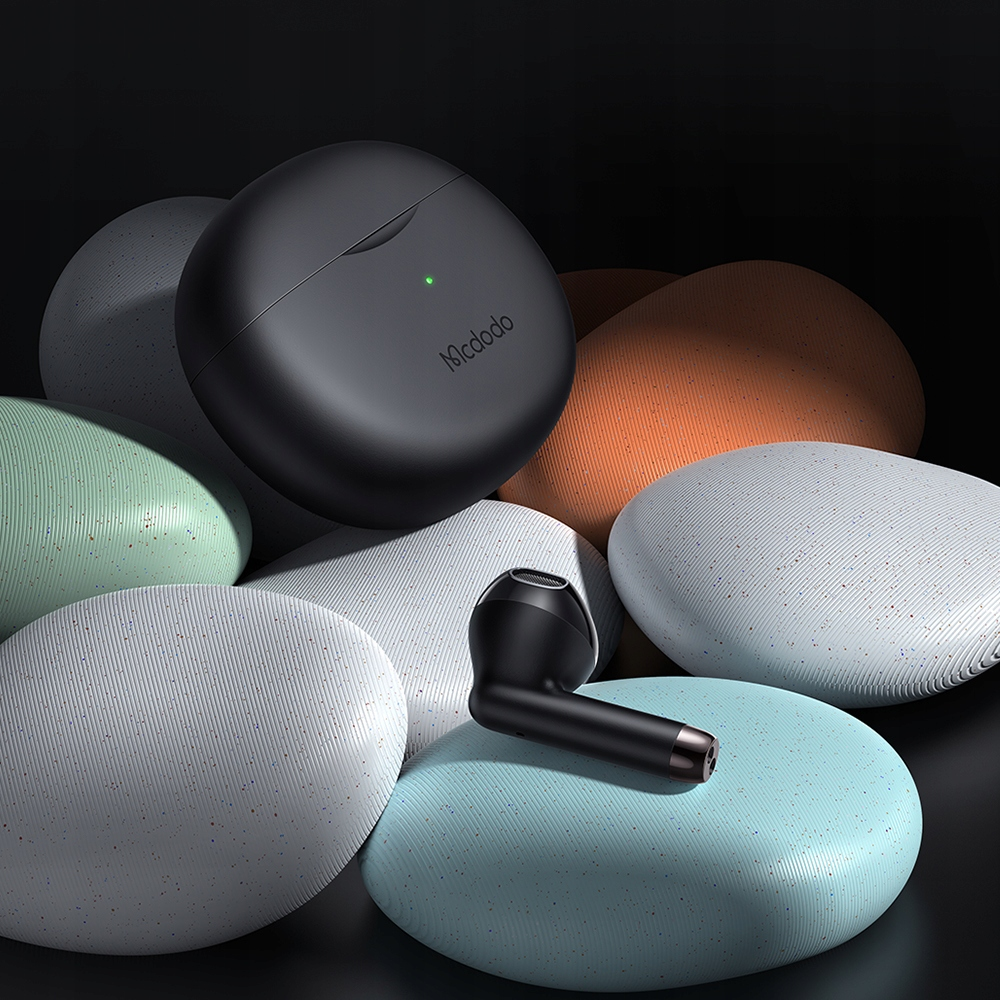 Auricolari wireless neri e custodia di ricarica su pietre decorative colorate con sfondo scuro.