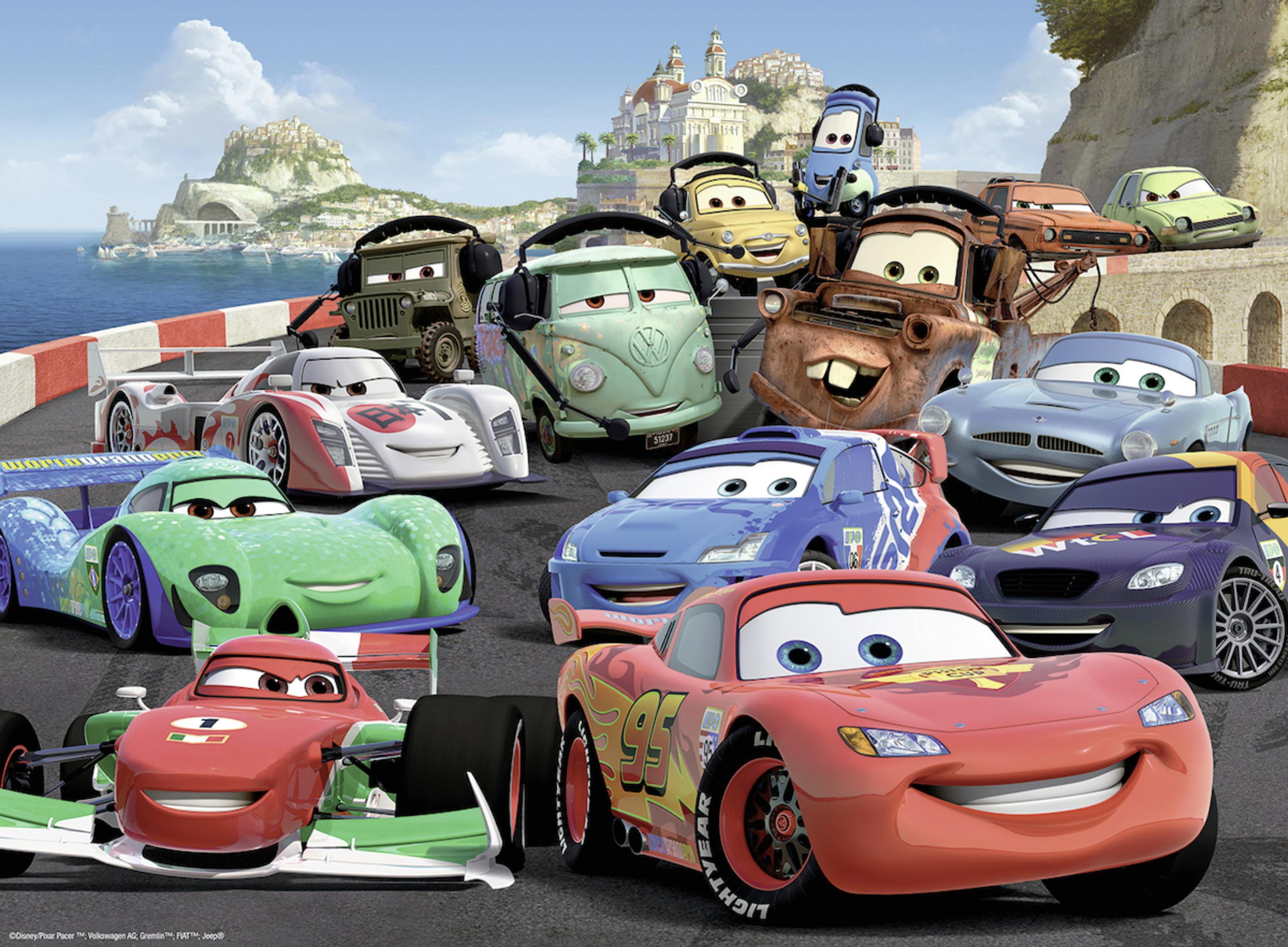 Verschiedene lebendige Autos aus dem Film Cars versammelt auf einer Rennstrecke mit einer Stadt und Meer im Hintergrund.