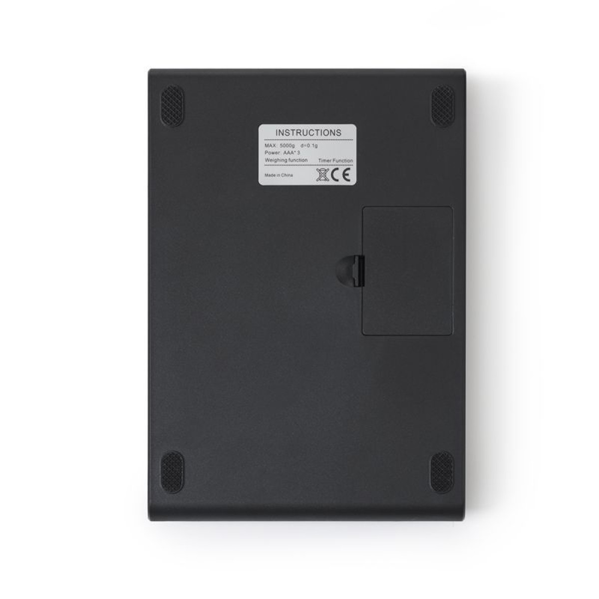 Die Unterseite einer schwarzen Küchenwaage mit vier rutschfesten Füßen, einem Batteriefach und einem weißen Aufkleber.