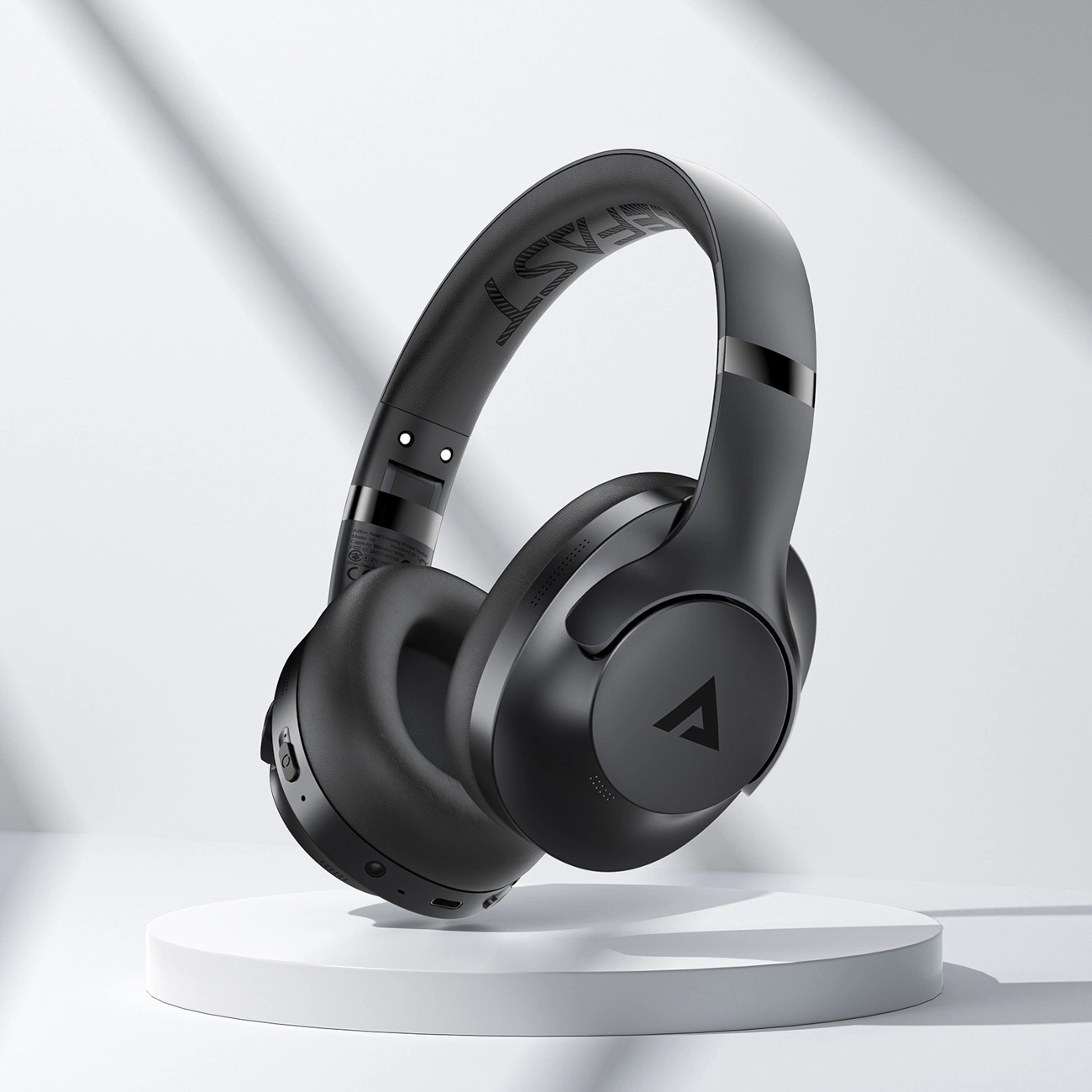 Cuffie over-ear nere con logo su piedistallo rotondo su sfondo bianco.