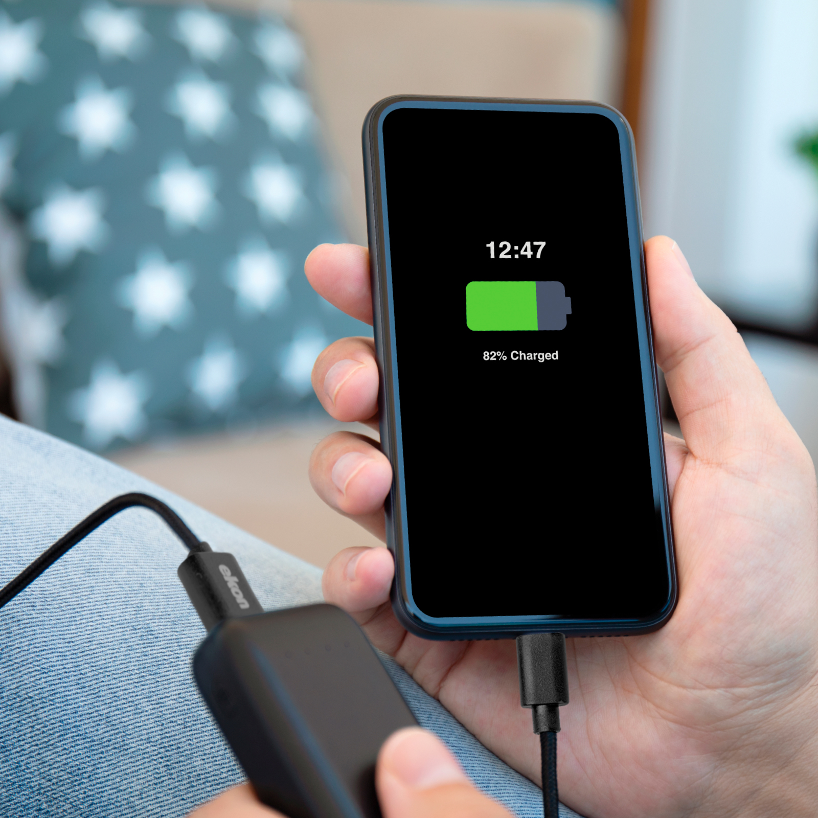 Handy in Hand zeigt 82% Ladung und ist mit Powerbank verbunden.