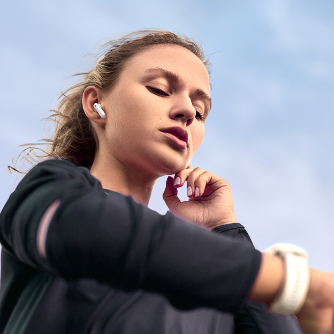 Una donna in abbigliamento sportivo con auricolari guarda lo smartwatch.