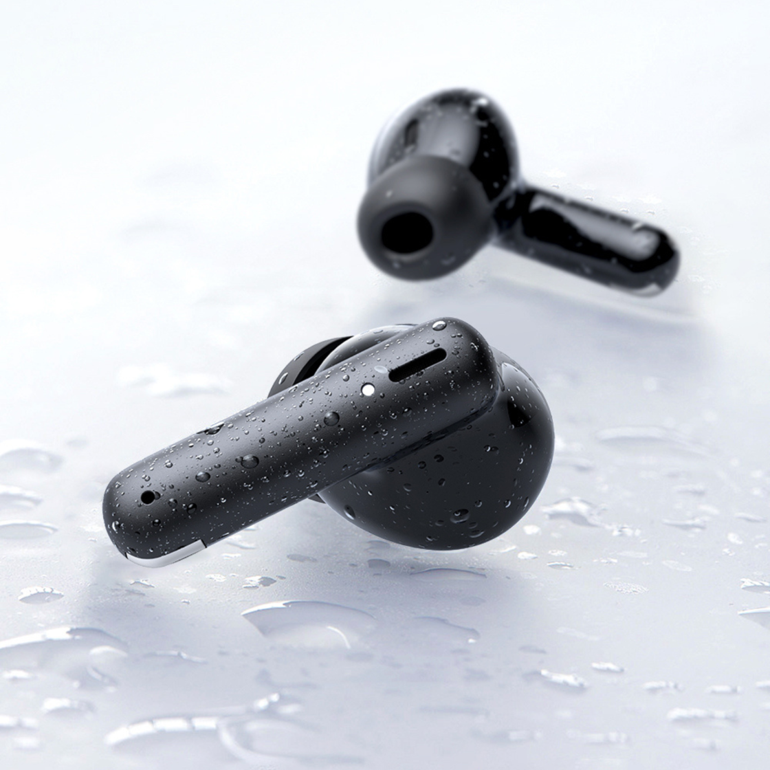 Due auricolari wireless neri coperti di gocce d'acqua su una superficie chiara e bagnata.