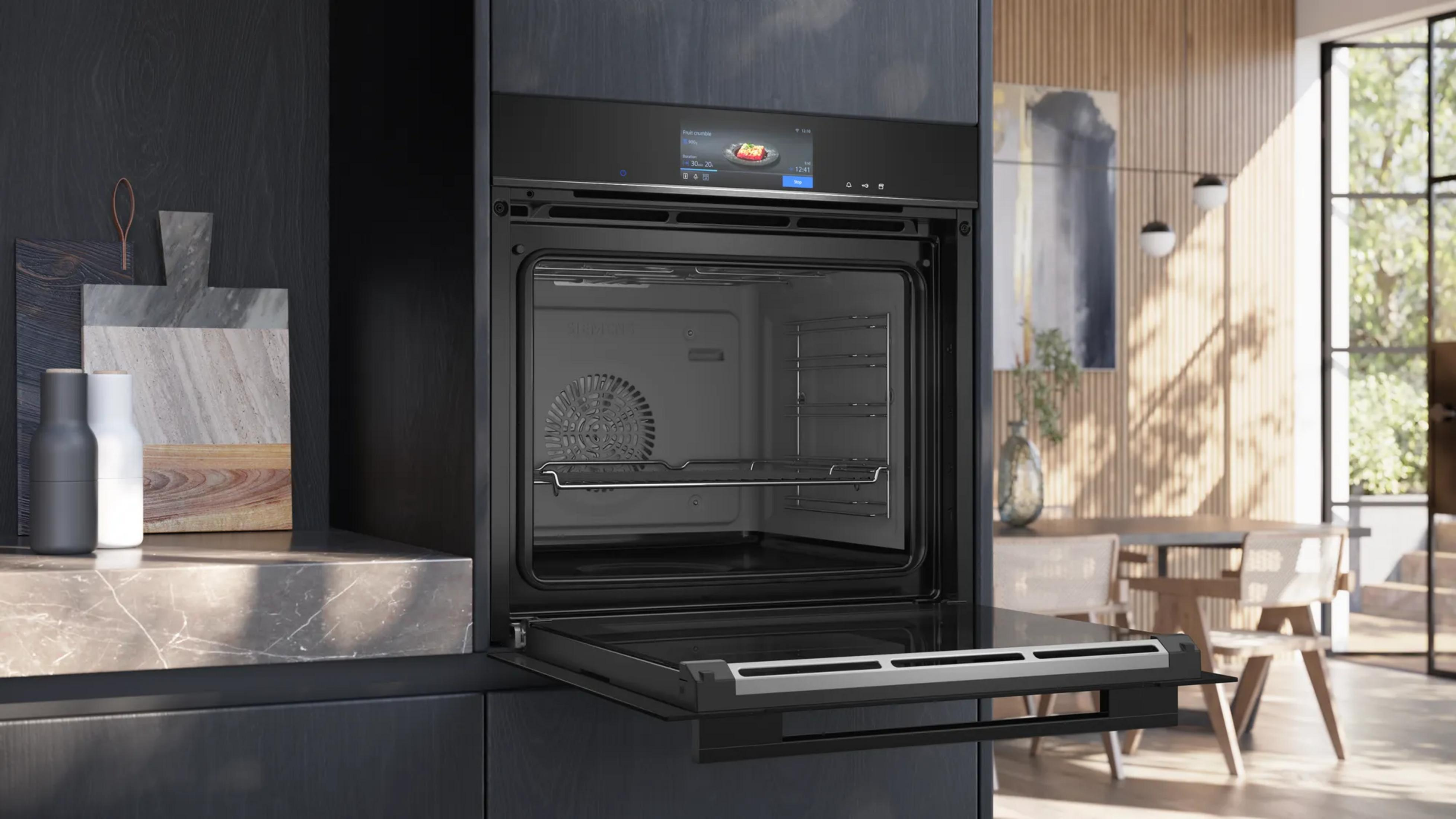 Four noir moderne avec porte ouverte dans une cuisine élégante aux accents de bois.