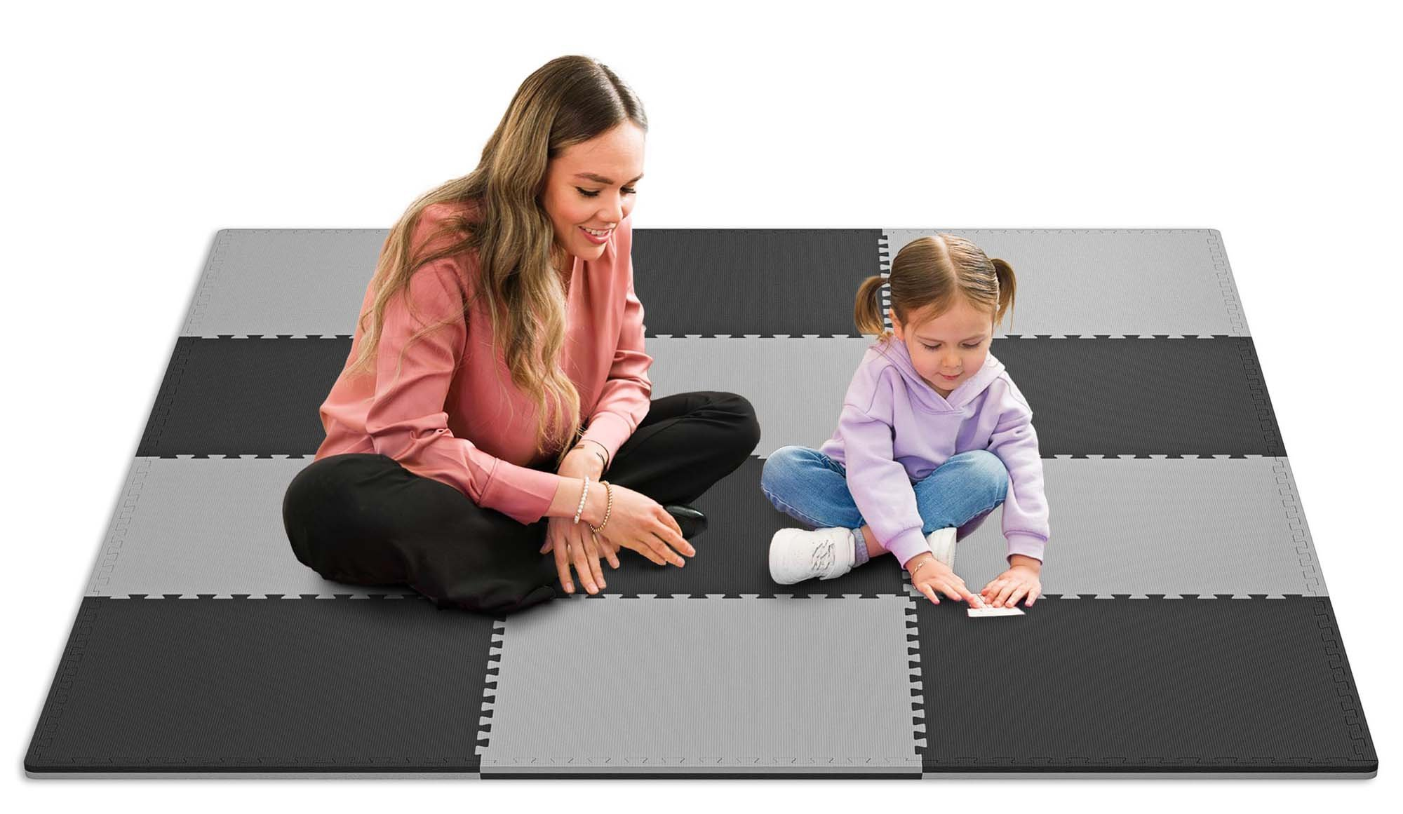 Eine Frau und ein kleines Mädchen sitzen auf einer grauen und schwarzen Schaumstoffmatte.