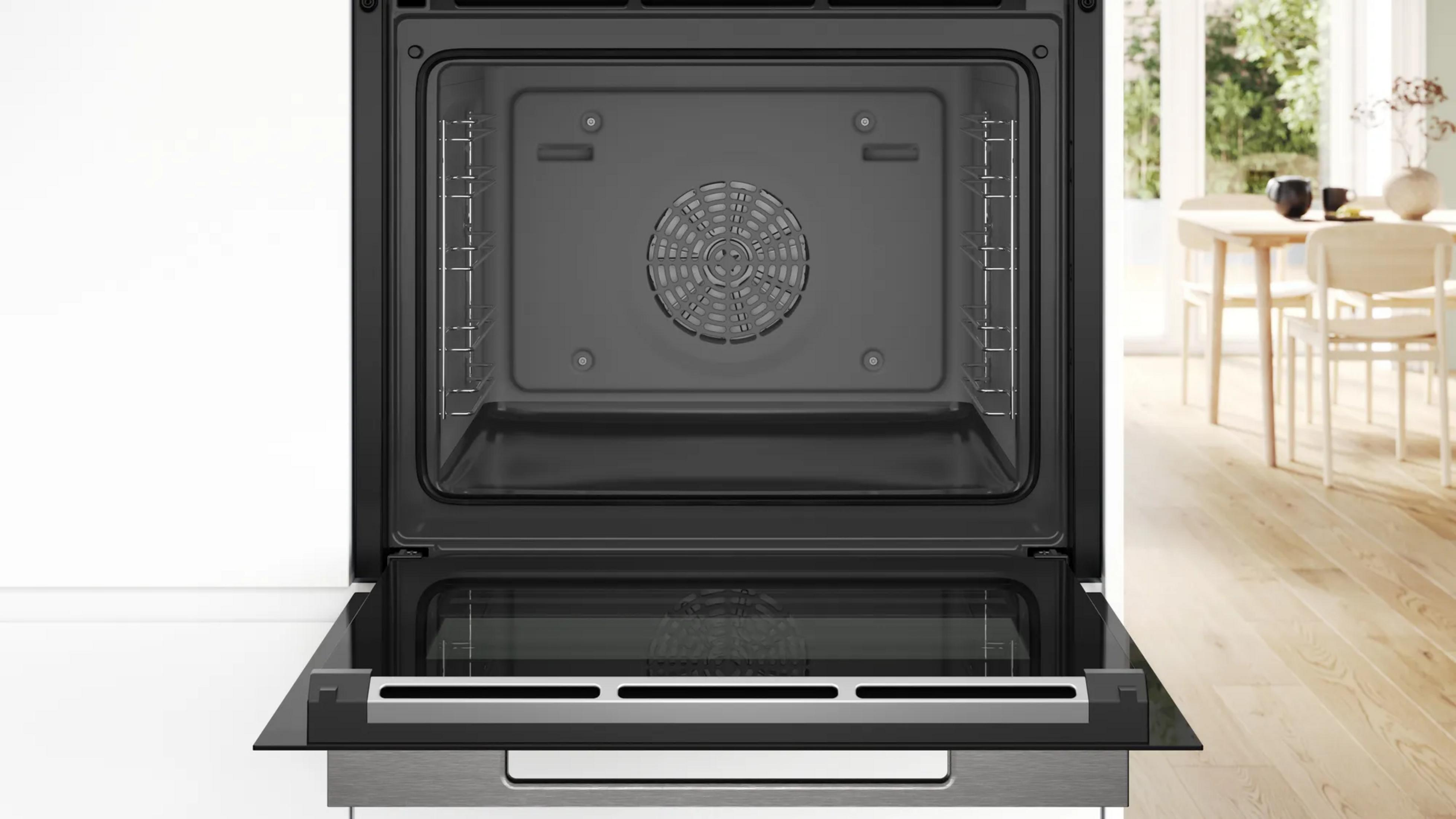 Un four noir ouvert et vide avec un ventilateur intégré et des grilles métalliques latérales dans une cuisine.