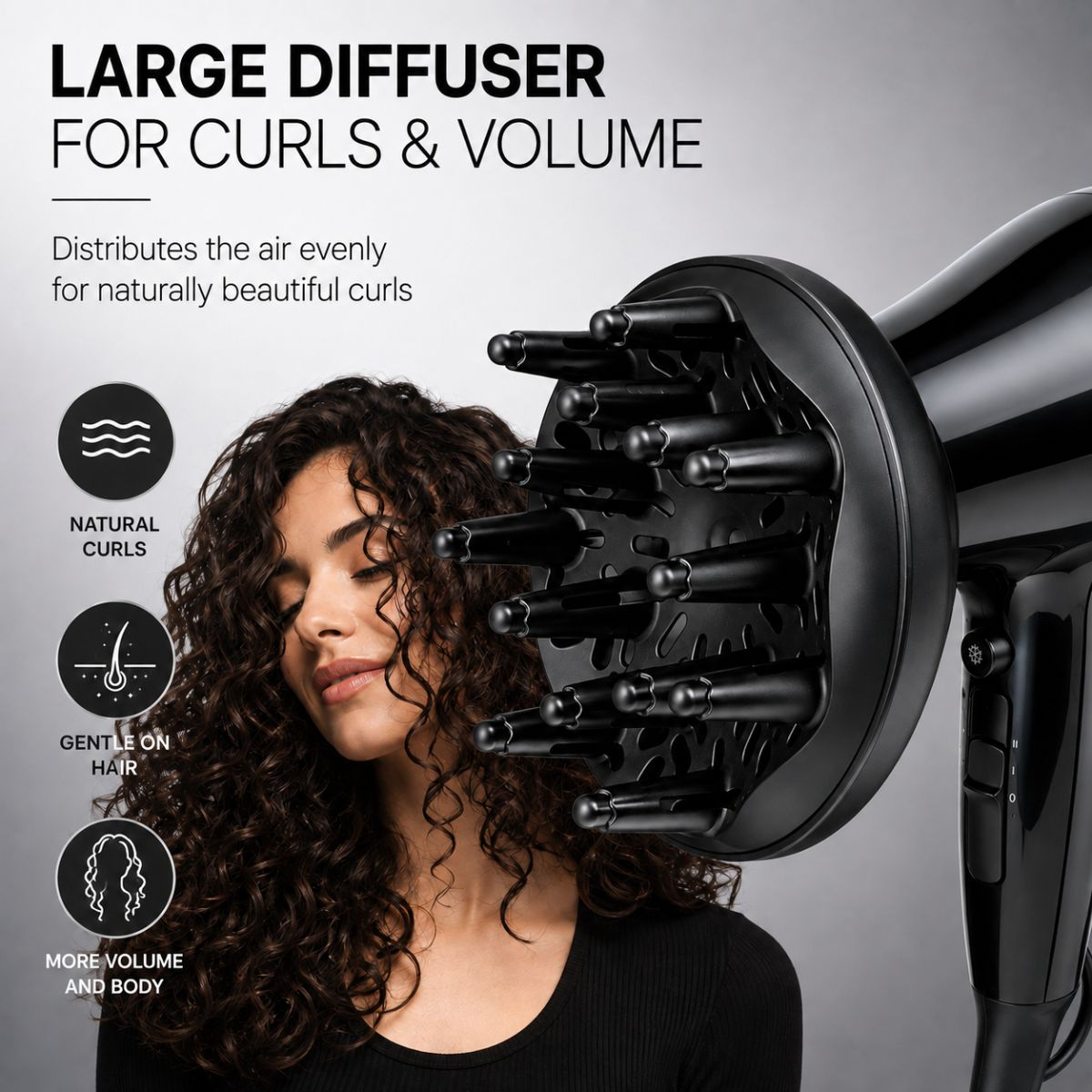 Eine Frau mit dunklen Locken neben einem schwarzen Haartrockner mit großem Diffusoraufsatz vor grauem Hintergrund.