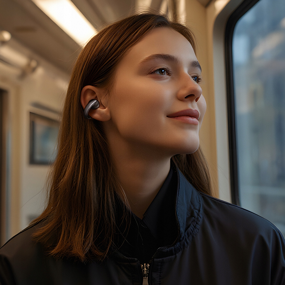 Una giovane donna con i capelli castani e auricolari neri guarda fuori dal finestrino di un treno.