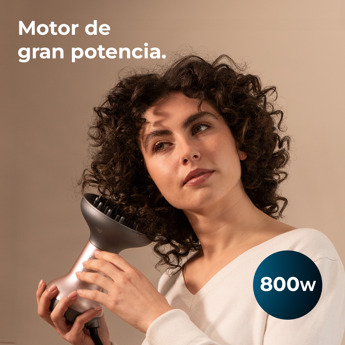 Una donna con i capelli ricci scuri si asciuga i capelli con un diffusore.