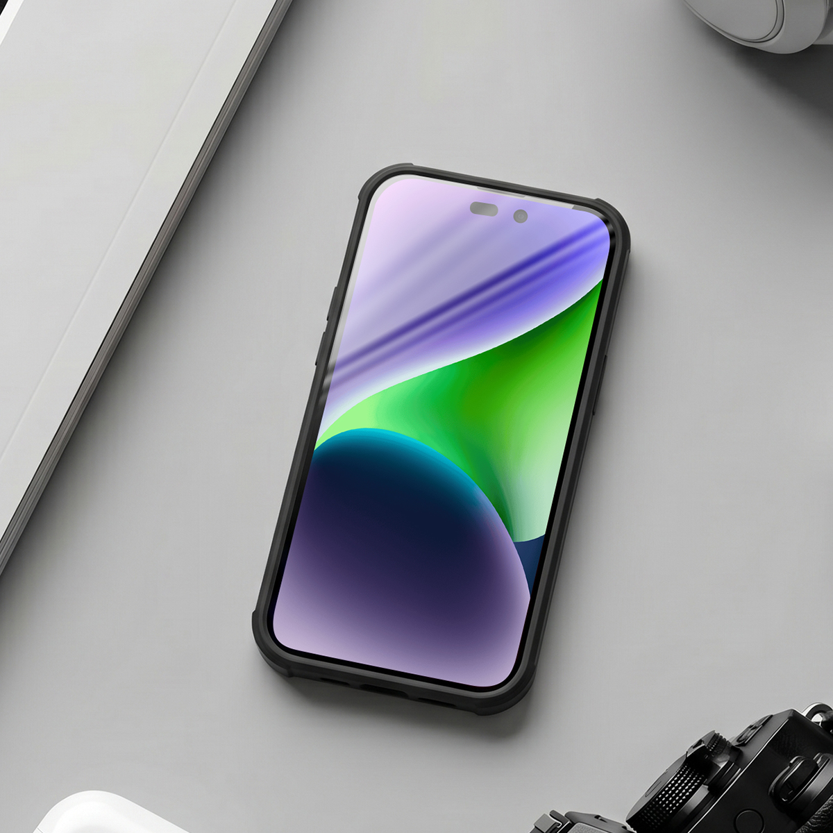 Uno smartphone con sfondo colorato su un tavolo grigio, accanto a un computer e una fotocamera.