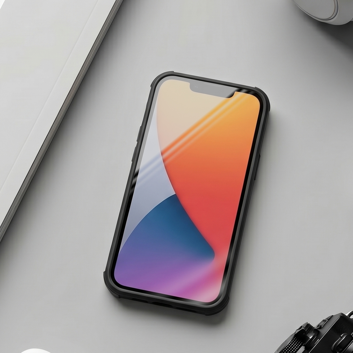 Uno smartphone con cover colorata poggia su un tavolo grigio vicino a un taccuino.