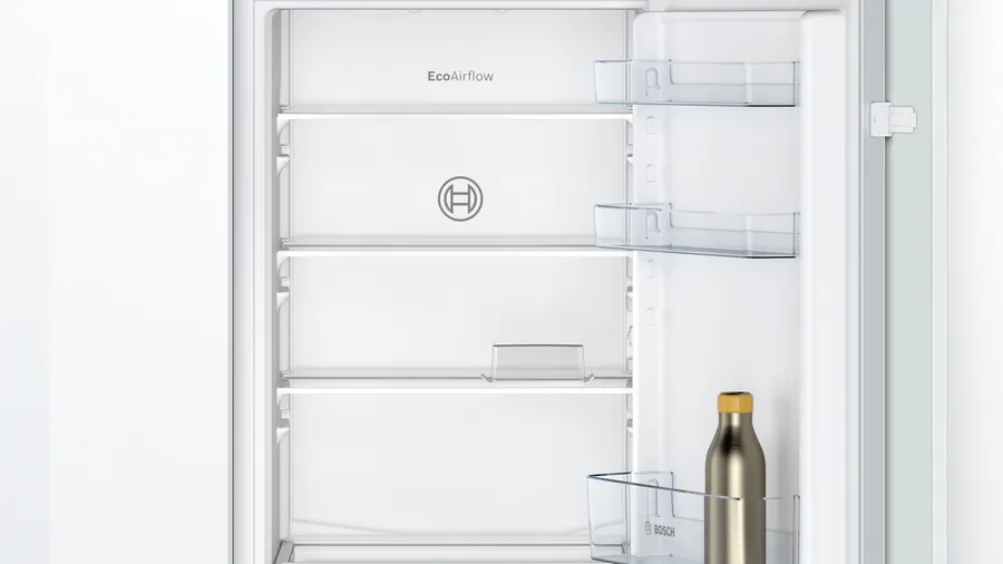 Innenraum eines weißen Bosch-Kühlschranks mit Glasböden und Türfächern, mit einer Flasche im untersten Fach.