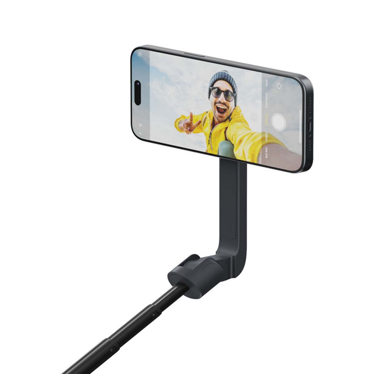 Siyah bir selfie çubuğu, sarı ceketli gülen bir adamın fotoğrafını gösteren bir akıllı telefon tutuyor.