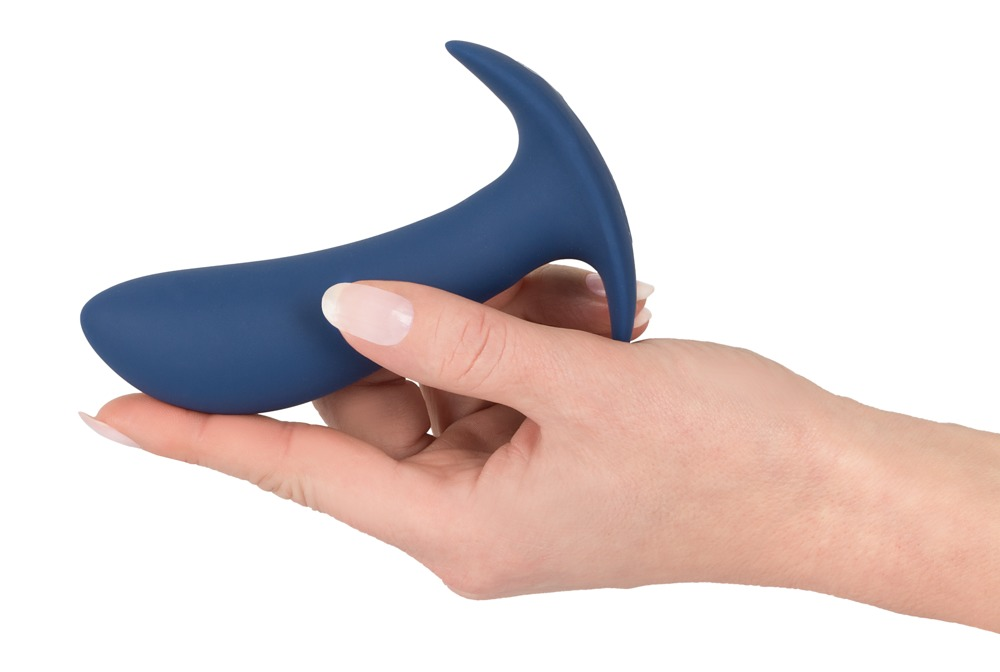 Eine Hand hält einen glatten, dunkelblauen Silikon-Analklammer-Dildo auf weißem Hintergrund.