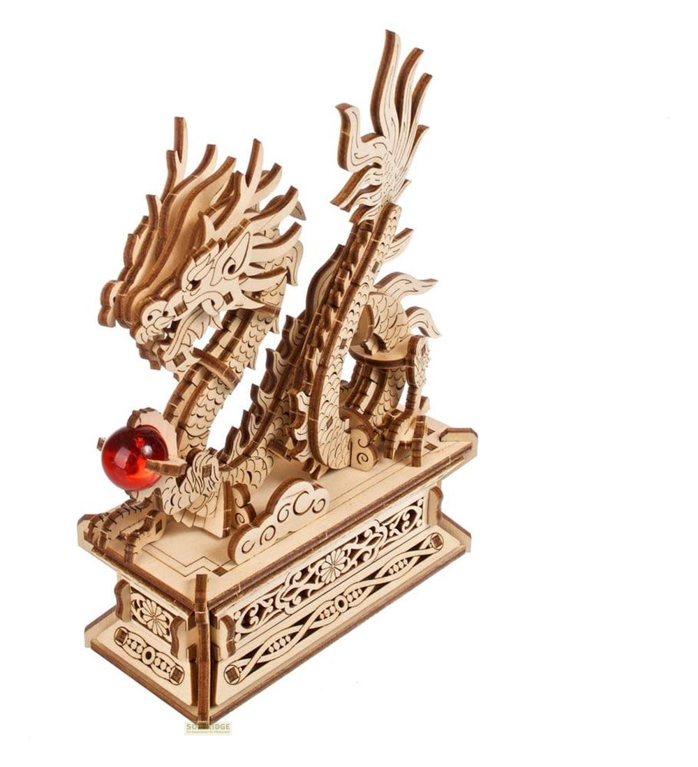 Ein hölzernes Drachenmodell mit einer roten Glaskugel auf einem kunstvollen Sockel.