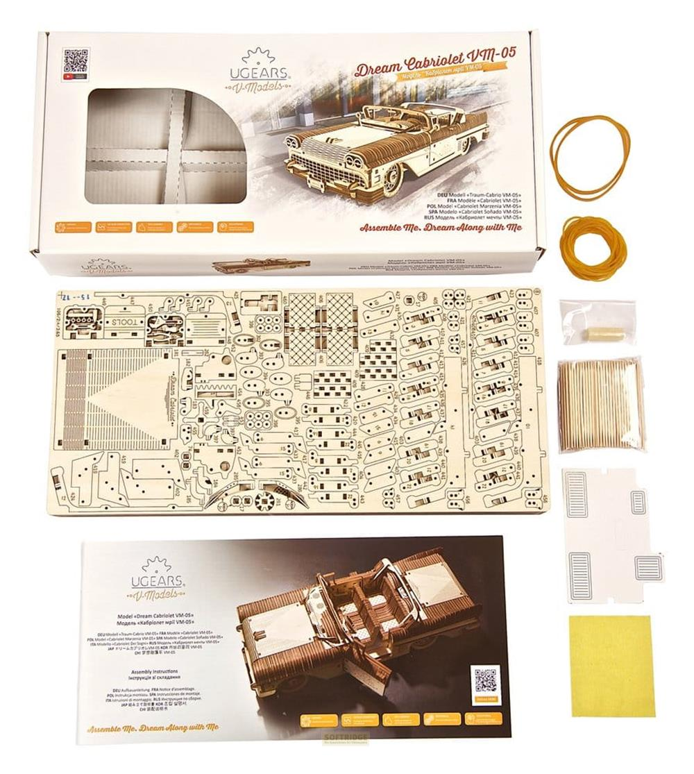 Holzmodellbausatz eines Cabrios mit Verpackung, Anleitung, Zahnstochern und Gummibändern auf weißem Hintergrund.