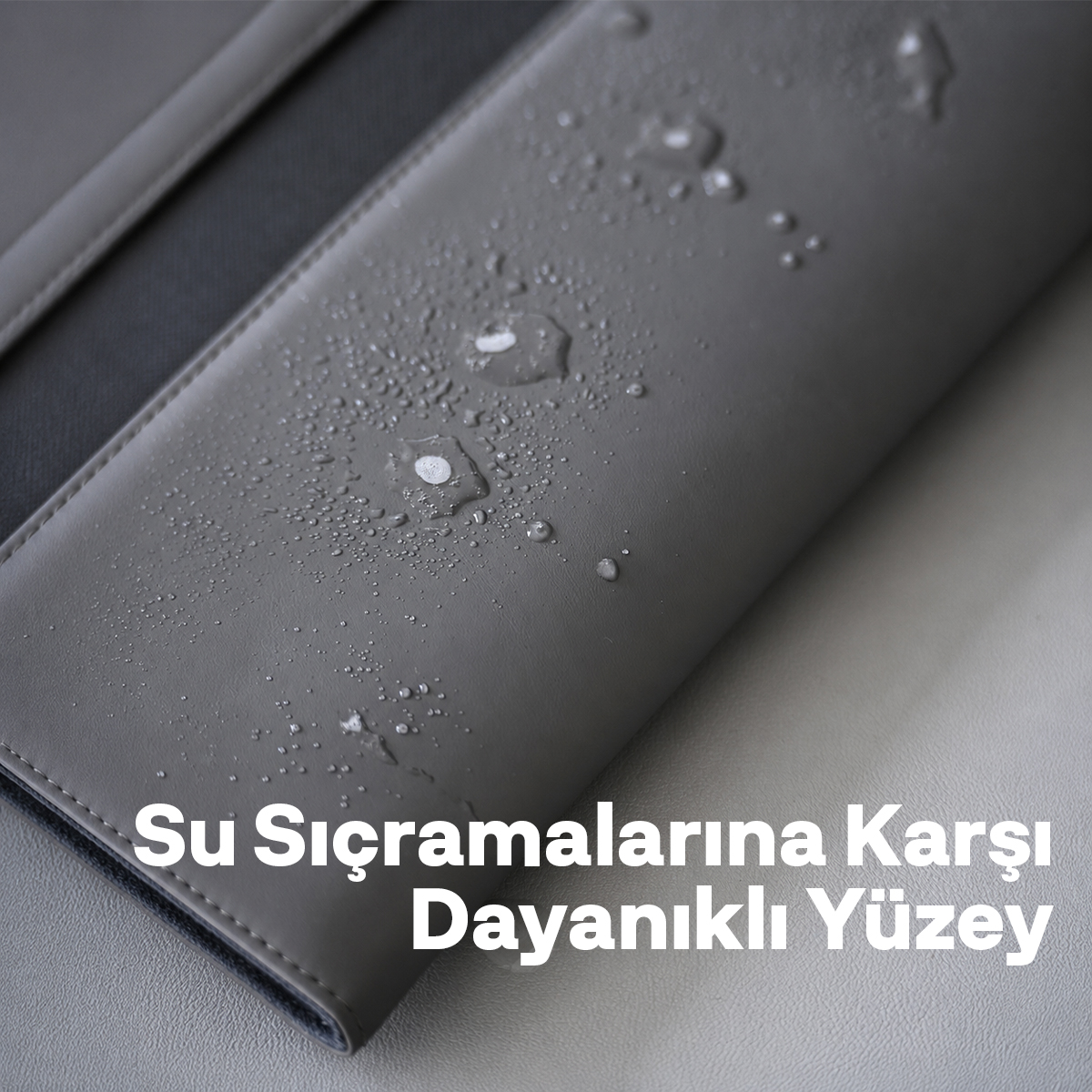 Su damlaları, dikişli kenarları olan şık gri deri yüzeyde toplanmıştır.