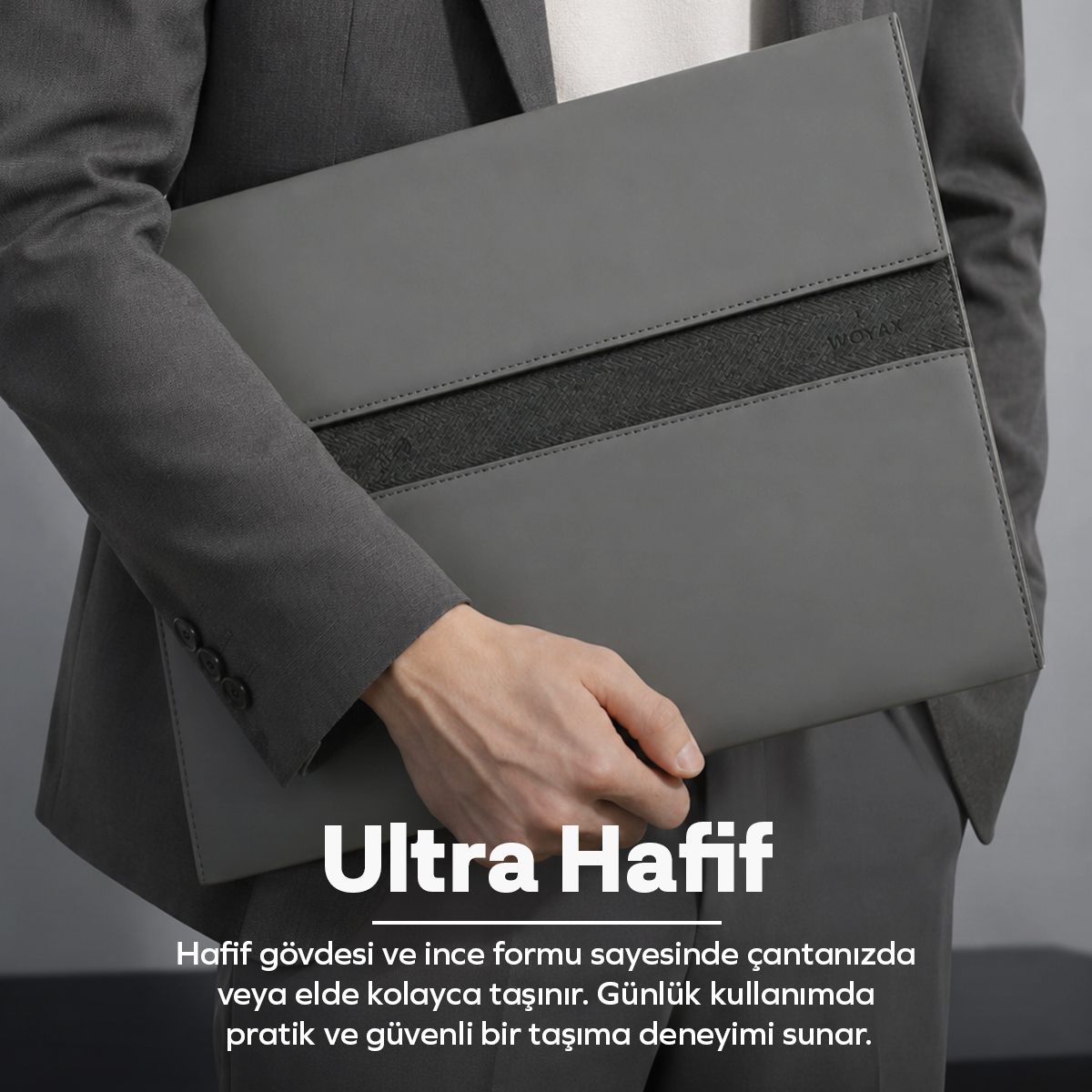 Gri takım elbiseli biri, koyu şeritli şık gri laptop çantasını ve altındaki yazıyı tutuyor.