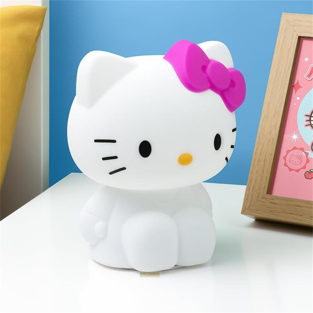 Eine weiße Hello Kitty Lampe mit rosa Schleife steht auf einer weißen Oberfläche neben einem Bilderrahmen.