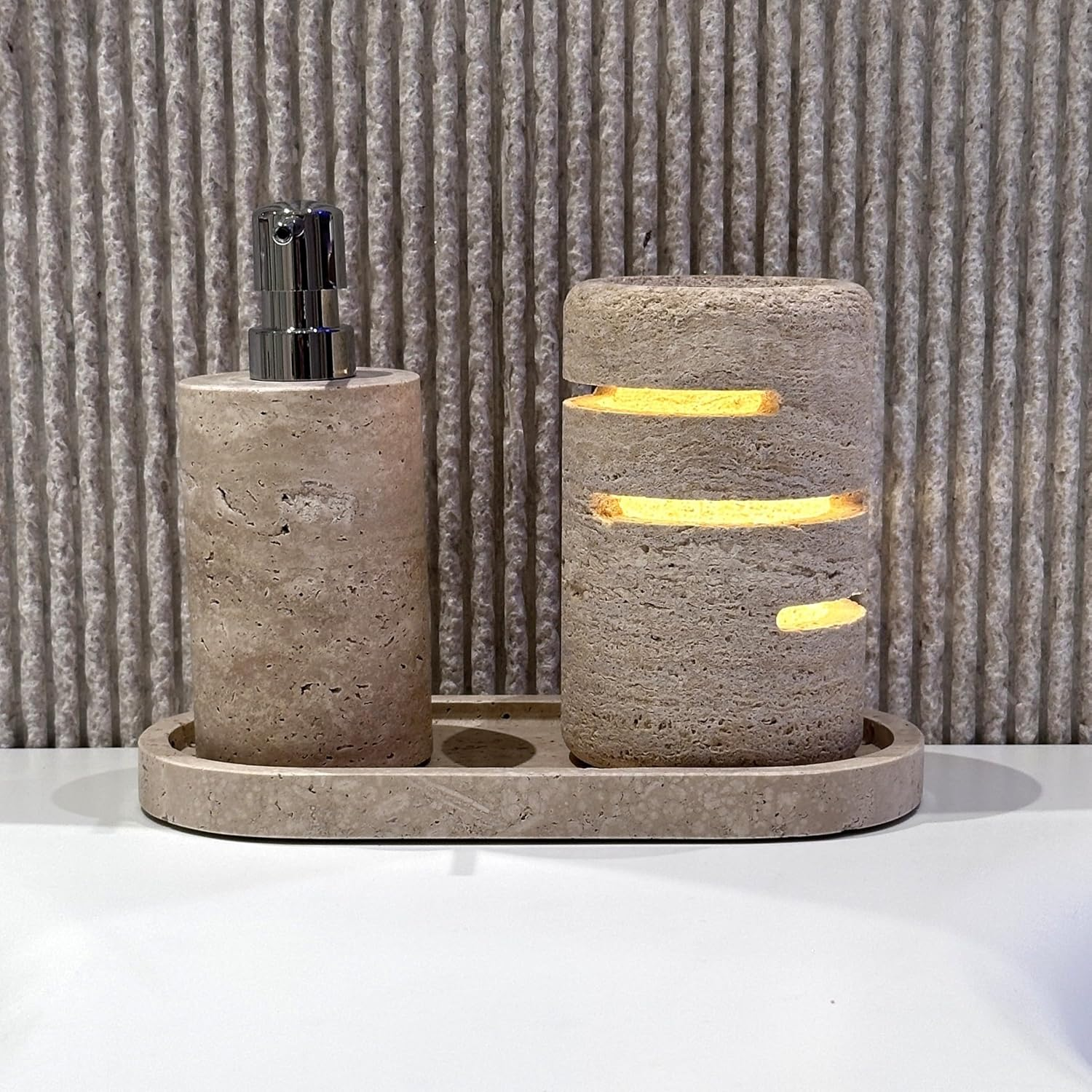 Beige Badaccessoires aus Stein auf einem Tablett vor einer strukturierten Wand.