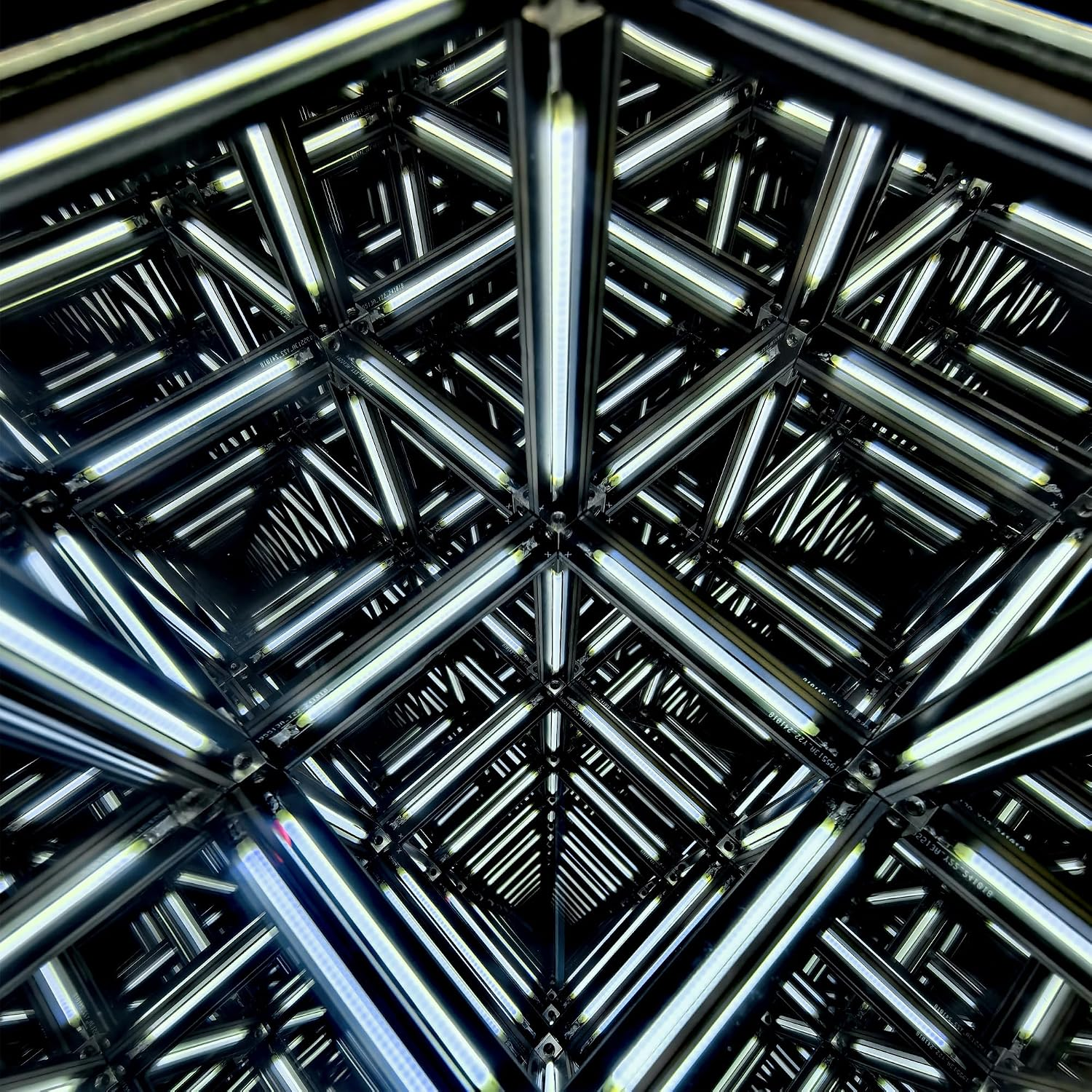 Ein geometrischer Rahmen aus beleuchteten LED-Röhren erzeugt ein unendliches, spiegelndes Mustertunnel.