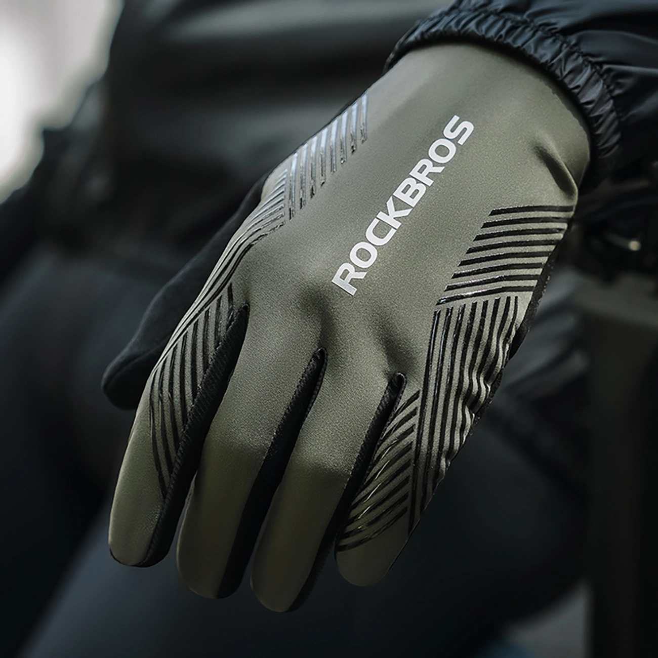 Un guanto da ciclismo Rockbros verde oliva con strisce nere e logo bianco, indossato su una mano.