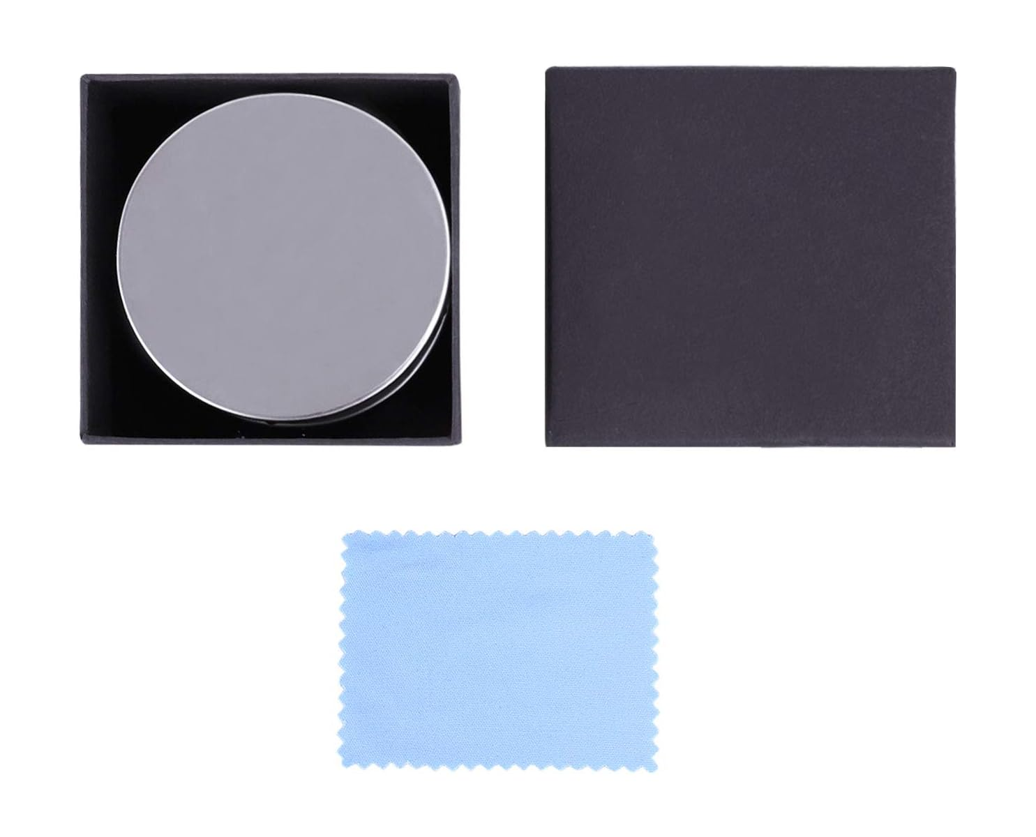 Eine schwarze Geschenkbox mit rundem Metalldeckel innen, geschlossener Deckel daneben und hellblaues Tuch unten.