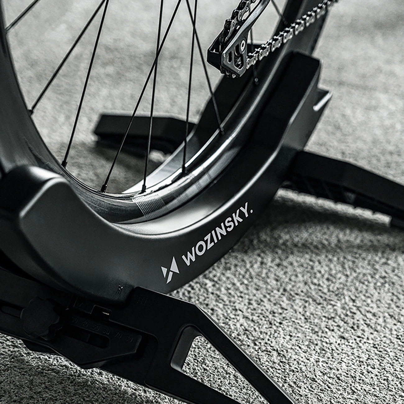 Una ruota di bicicletta nera in un supporto da terra Wozinsky su tappeto.