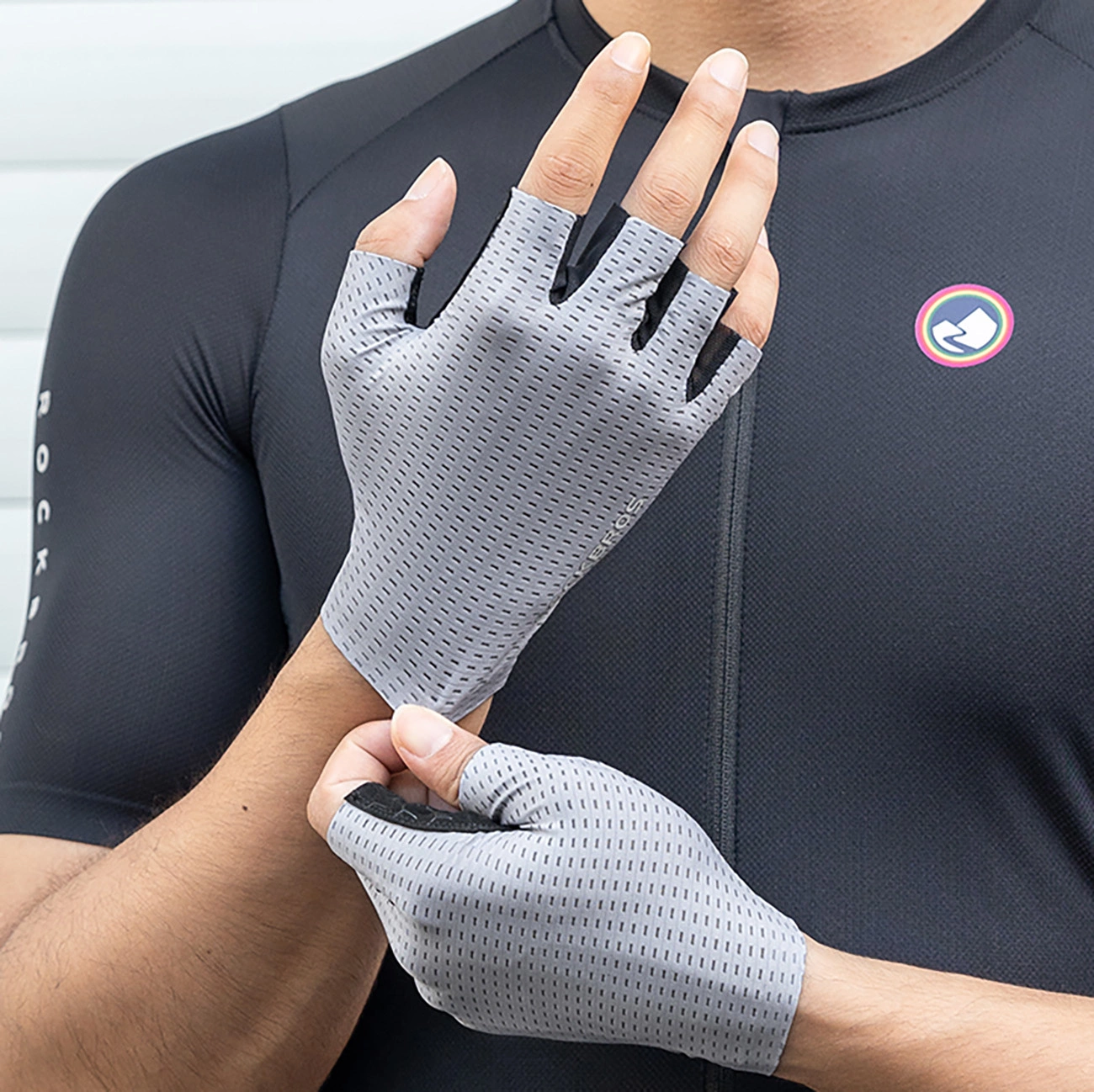 Un ciclista indossa guanti da ciclismo grigi senza dita in rete davanti a una maglia nera.