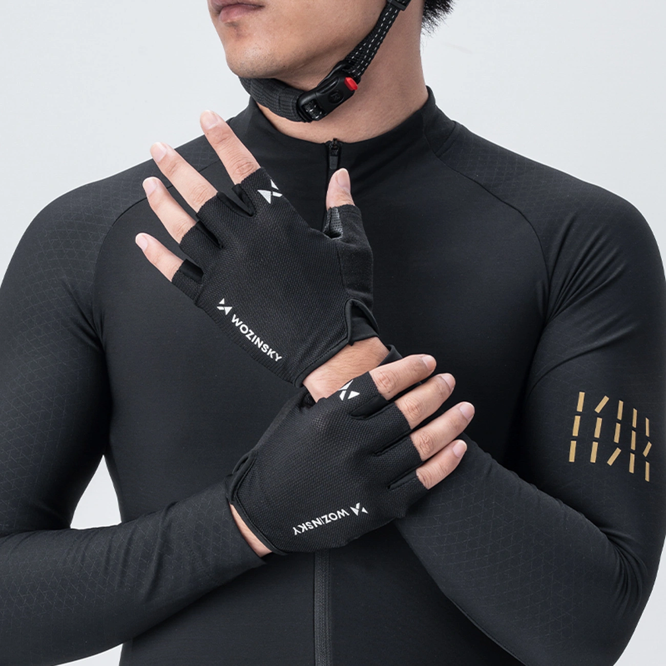 Un ciclista con maglia nera e casco mostra guanti da ciclismo senza dita neri Wozinsky.