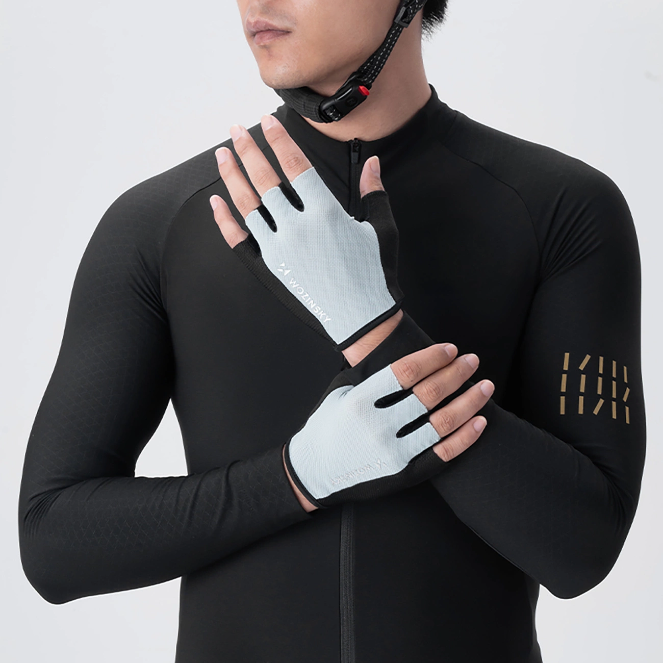 Un ciclista in maglia nera e casco indossa guanti da ciclismo senza dita azzurri su sfondo neutro.
