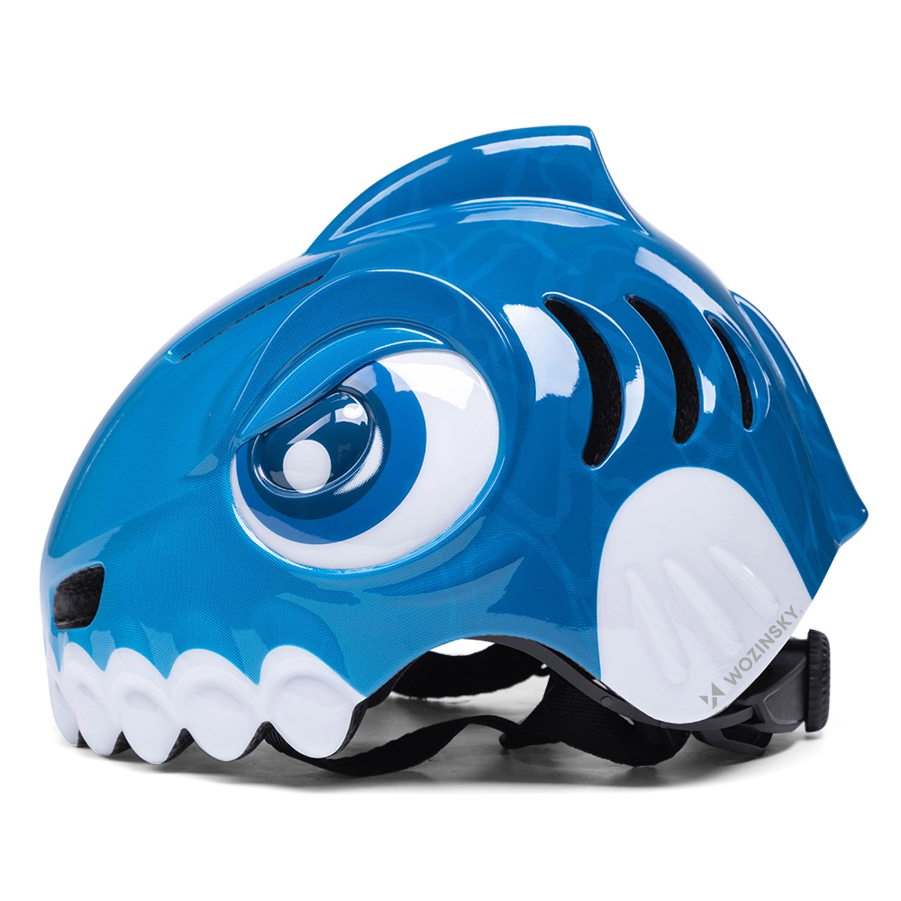 Un casco da bambino blu a tema squalo con grandi occhi, denti bianchi e pinna dorsale su sfondo bianco.