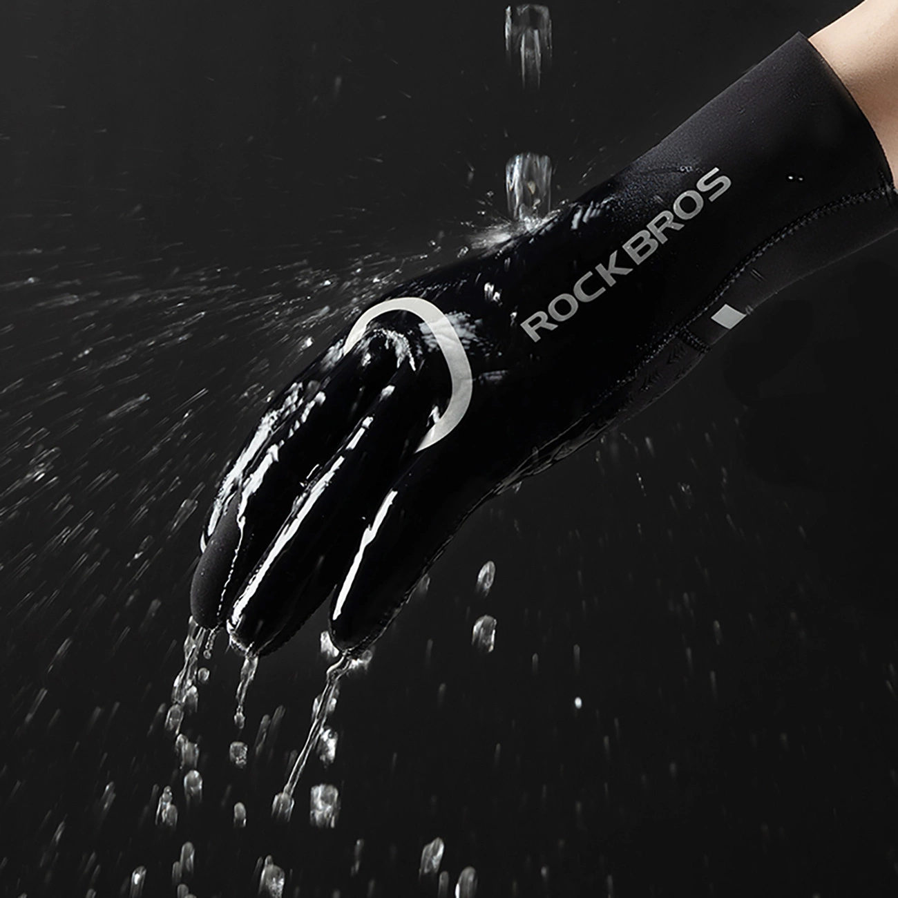 Un guanto nero Rockbros sotto l'acqua corrente su sfondo scuro.