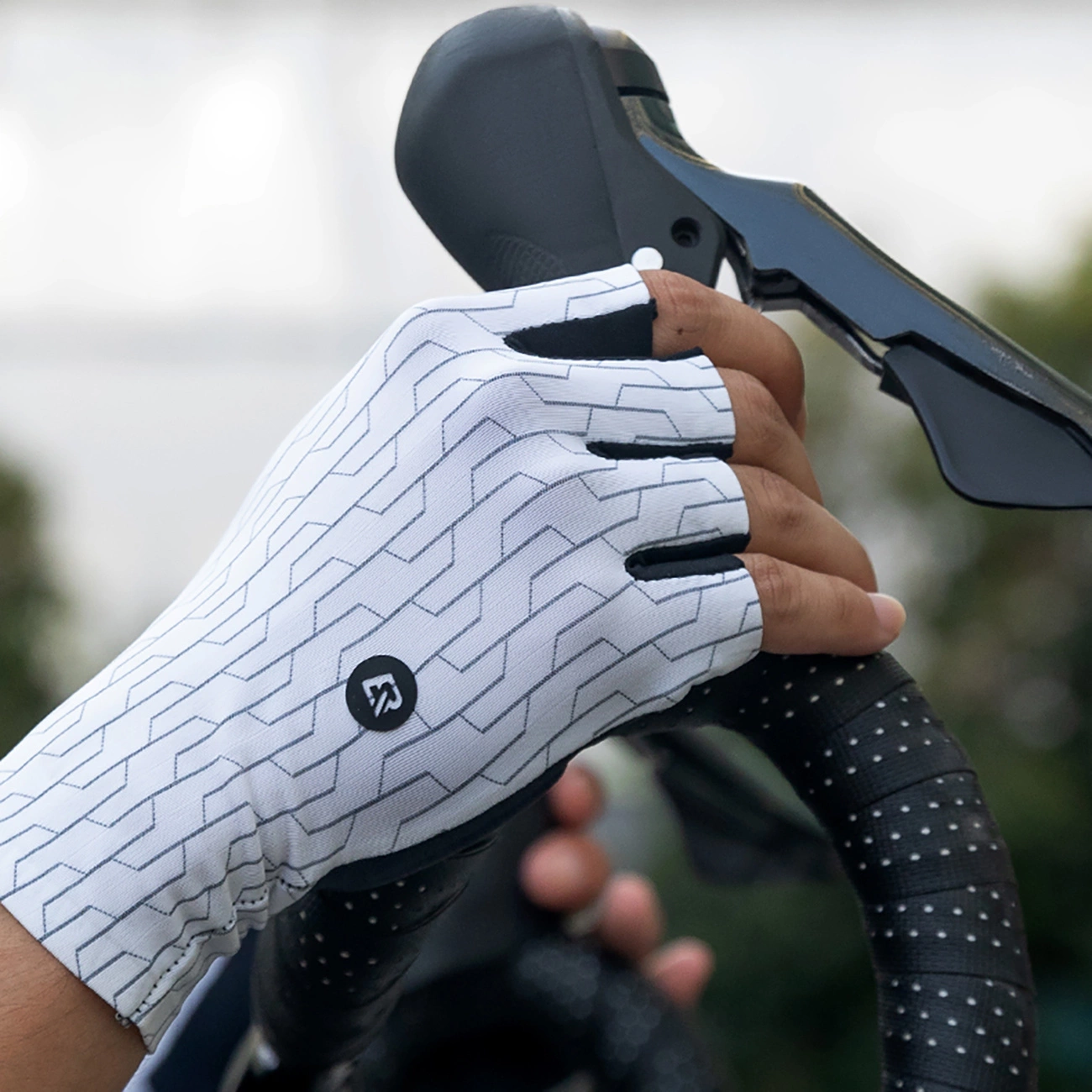 Una mano con un guanto da ciclismo bianco e nero stringe il manubrio.