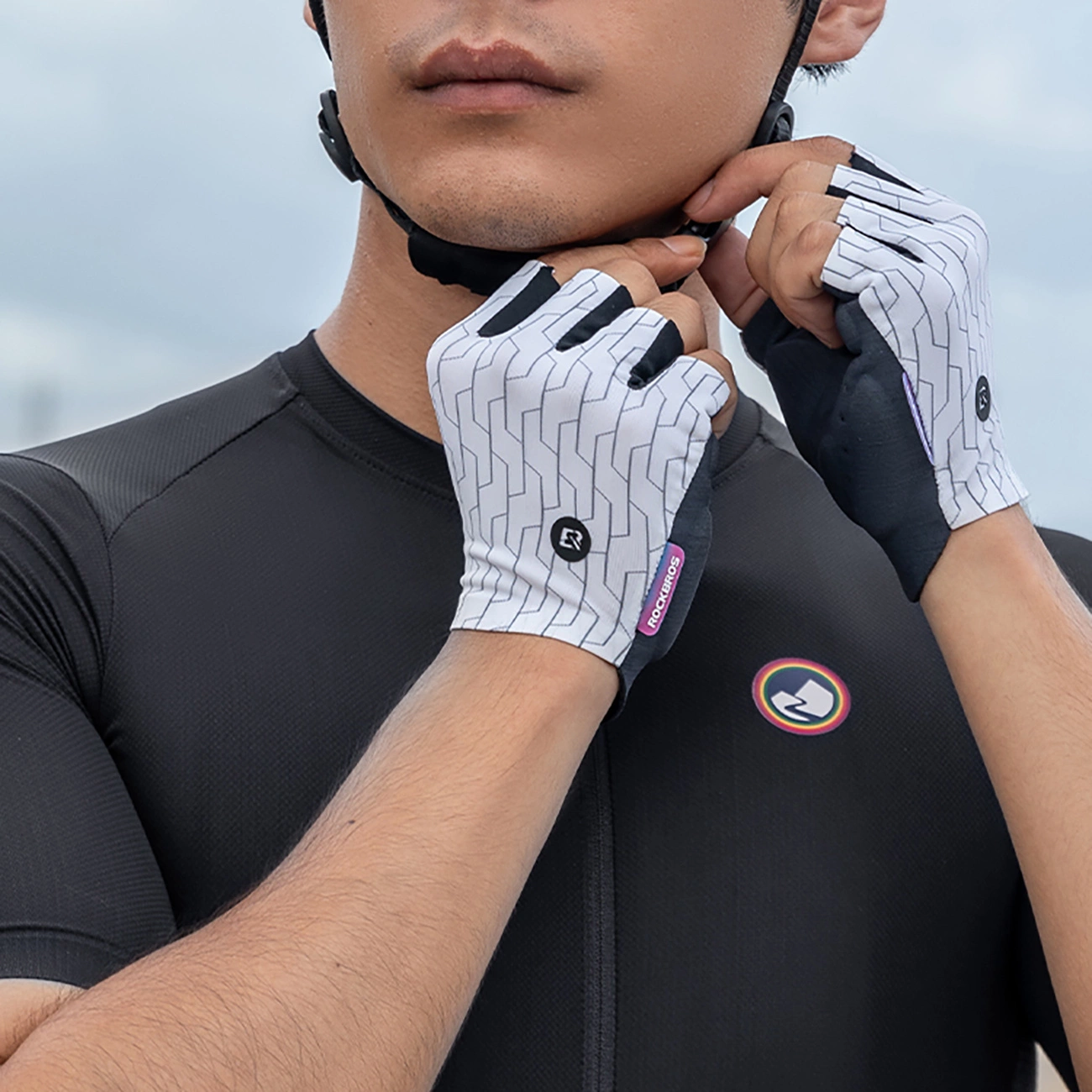 Un ciclista con maglia nera e casco sistema i suoi guanti da ciclismo fantasia.
