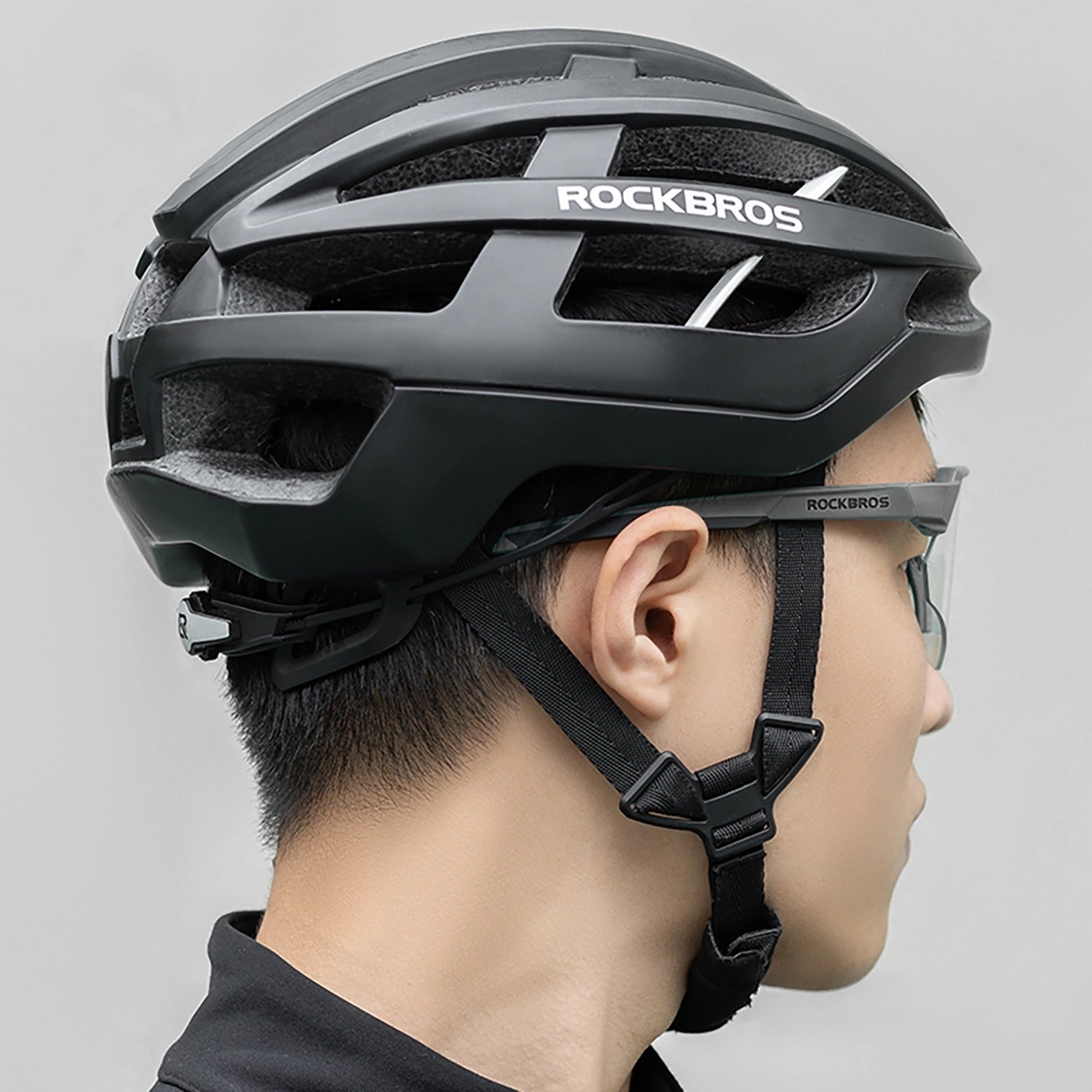Profilo laterale di una persona con casco da ciclismo Rockbros nero e occhiali coordinati su sfondo chiaro.