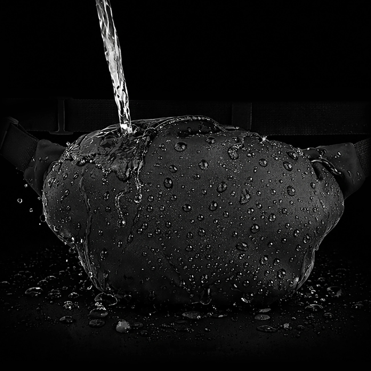 Dell'acqua viene versata su un marsupio nero coperto di gocce d'acqua.