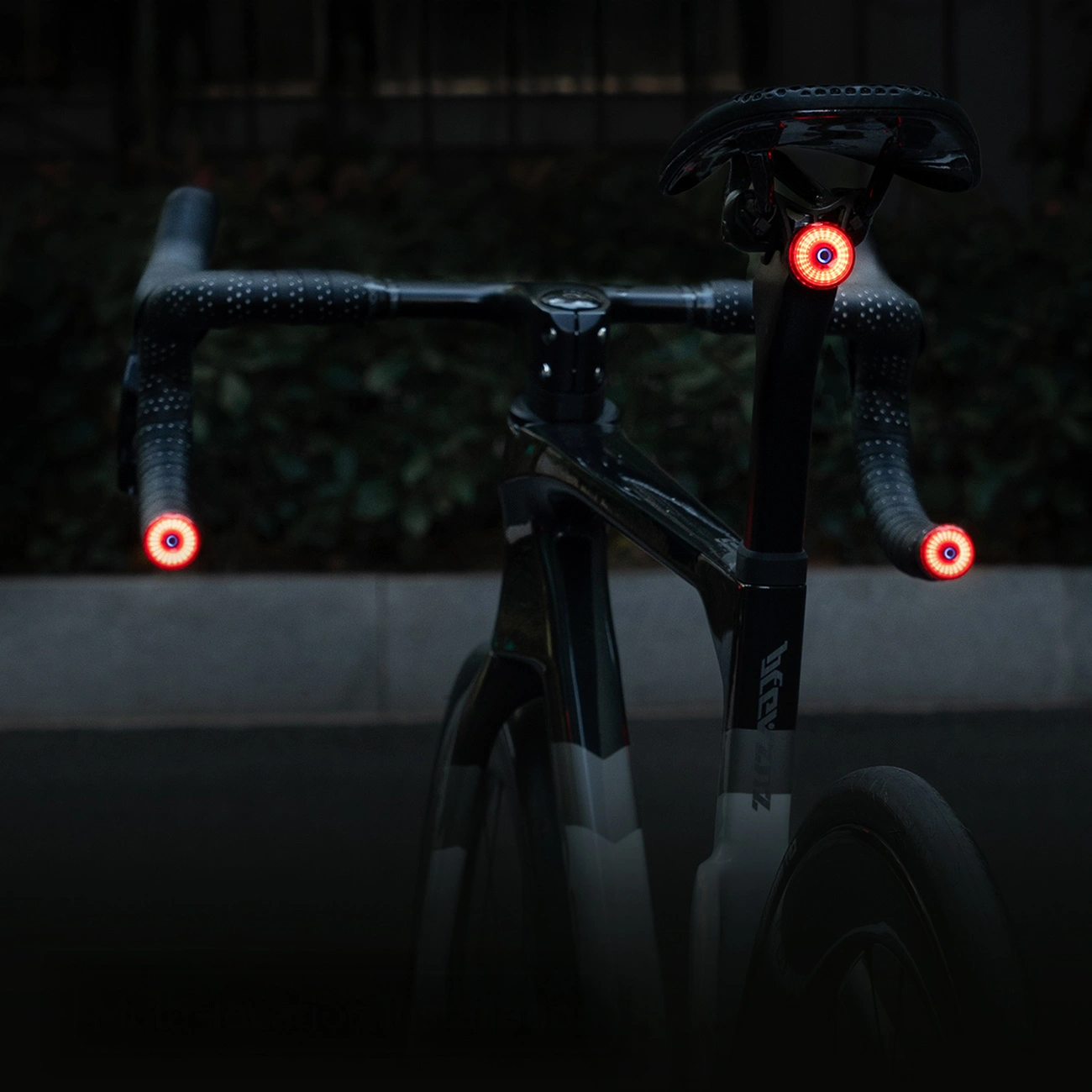 Una bicicletta nera con luci LED rosse brillanti sul manubrio e sul reggisella di notte.
