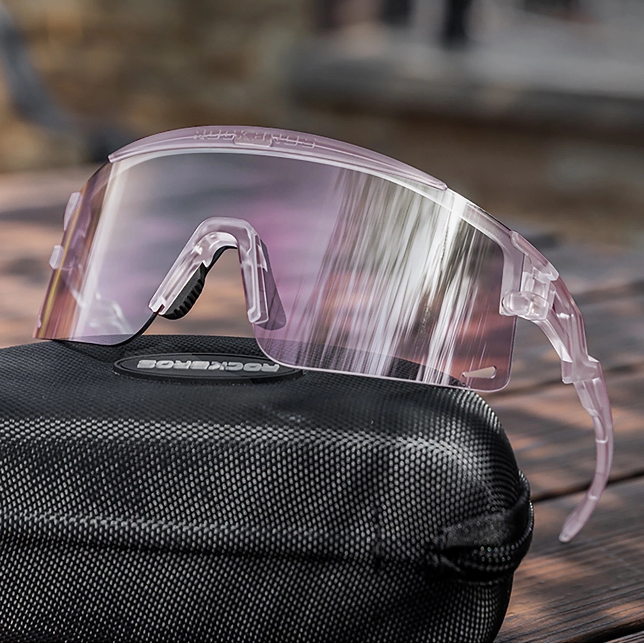 Occhiali sportivi rosa su astuccio nero su tavolo in legno.