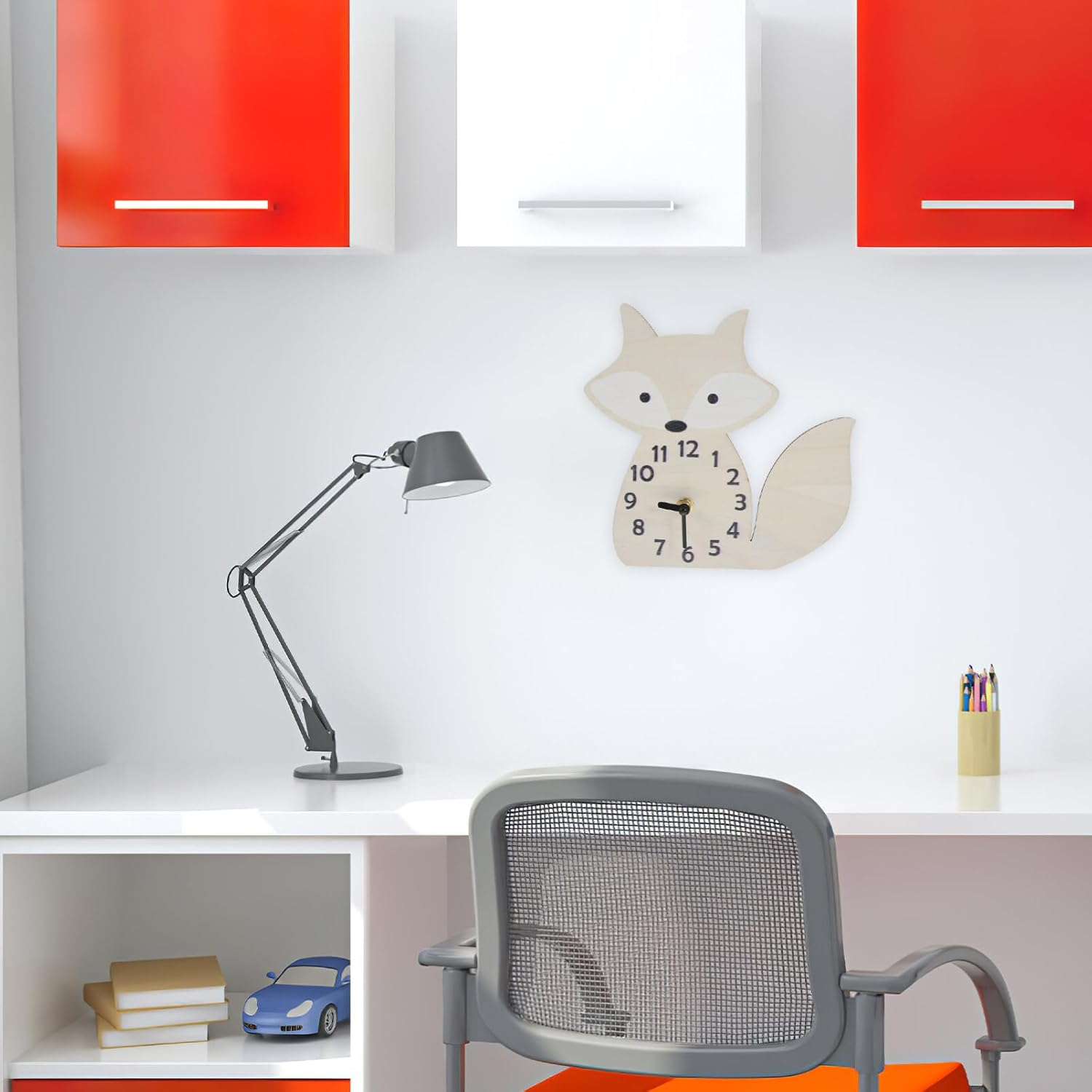 Ein weißer Schreibtisch mit grauem Stuhl, dunkler Lampe, fuchsförmiger Wanduhr und rot-weißen Hängeschränken.