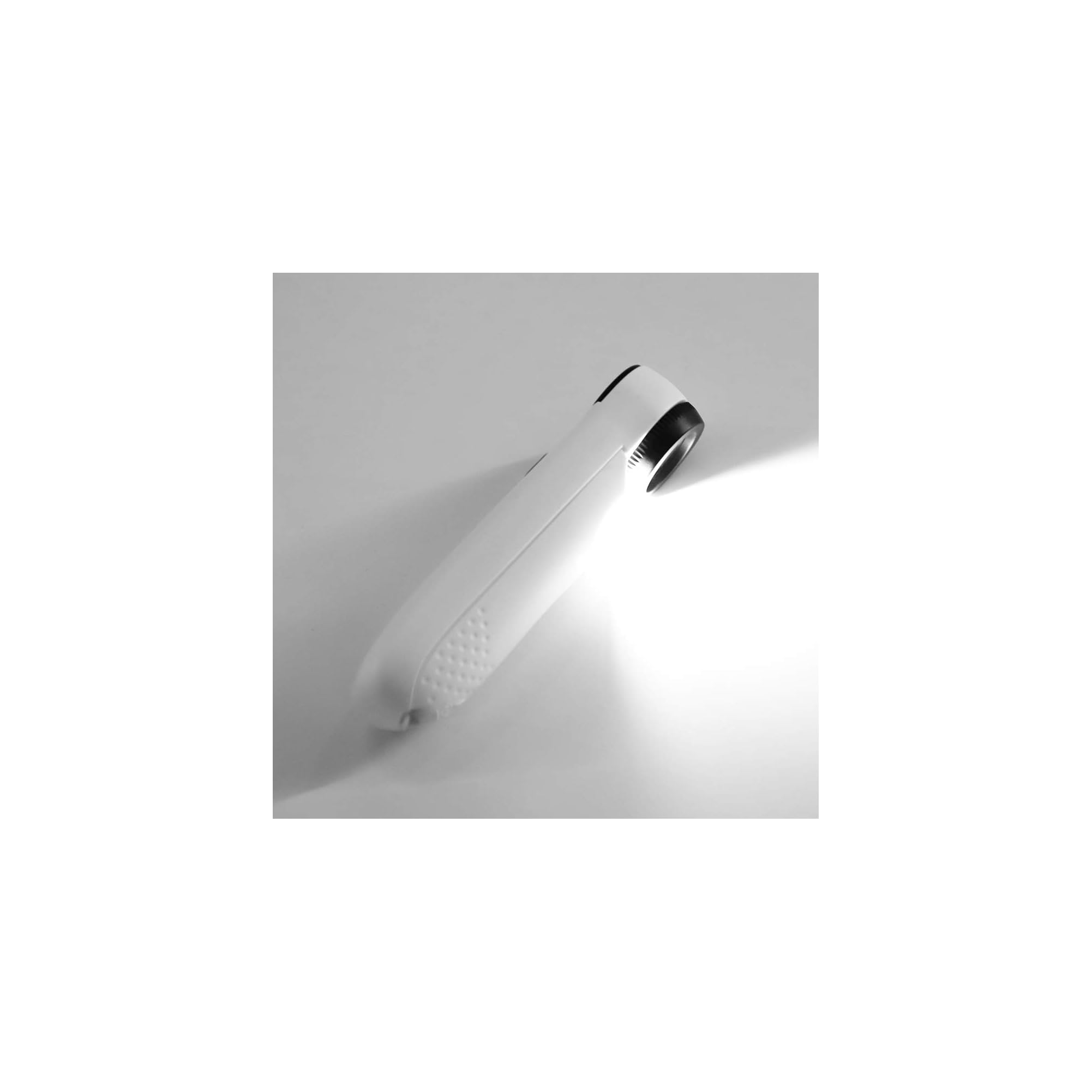Eine weiße Handlupe mit Licht liegt auf einem grauen Hintergrund.