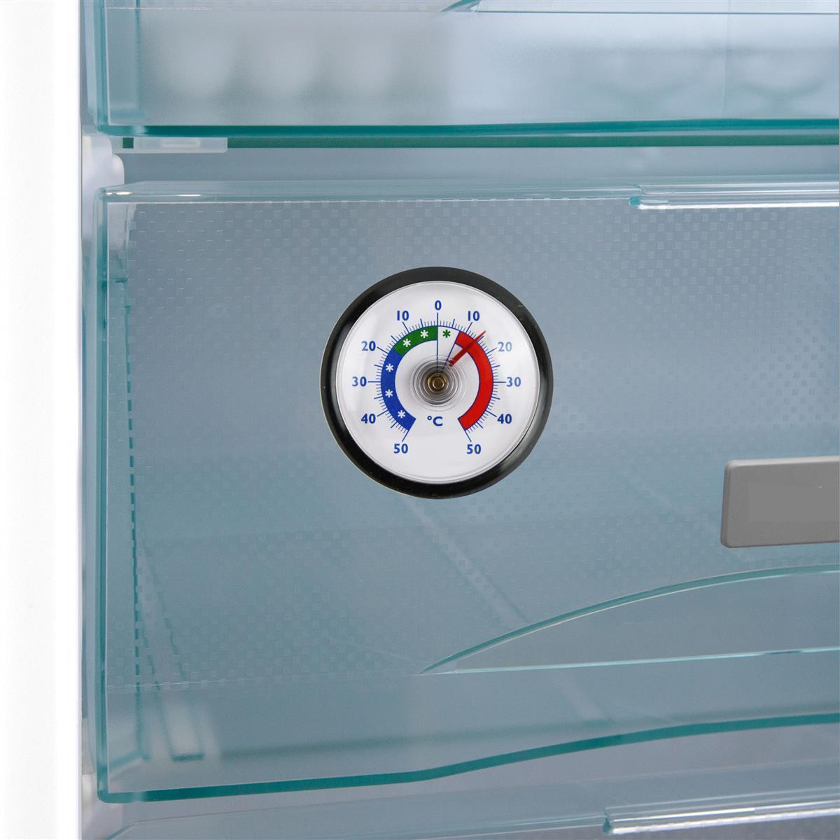 Ein kreisrundes Thermometer mit rotem, grünem und blauem Bereich ist an einer durchsichtigen Kühlschranktür befestigt.