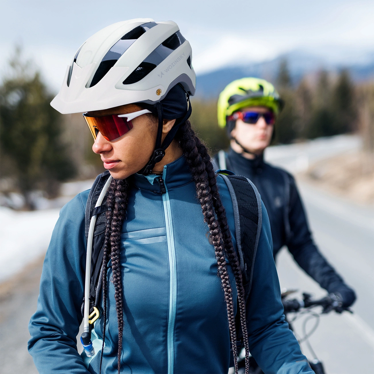 Due ciclisti con caschi e occhiali da sole su una strada all'aperto.