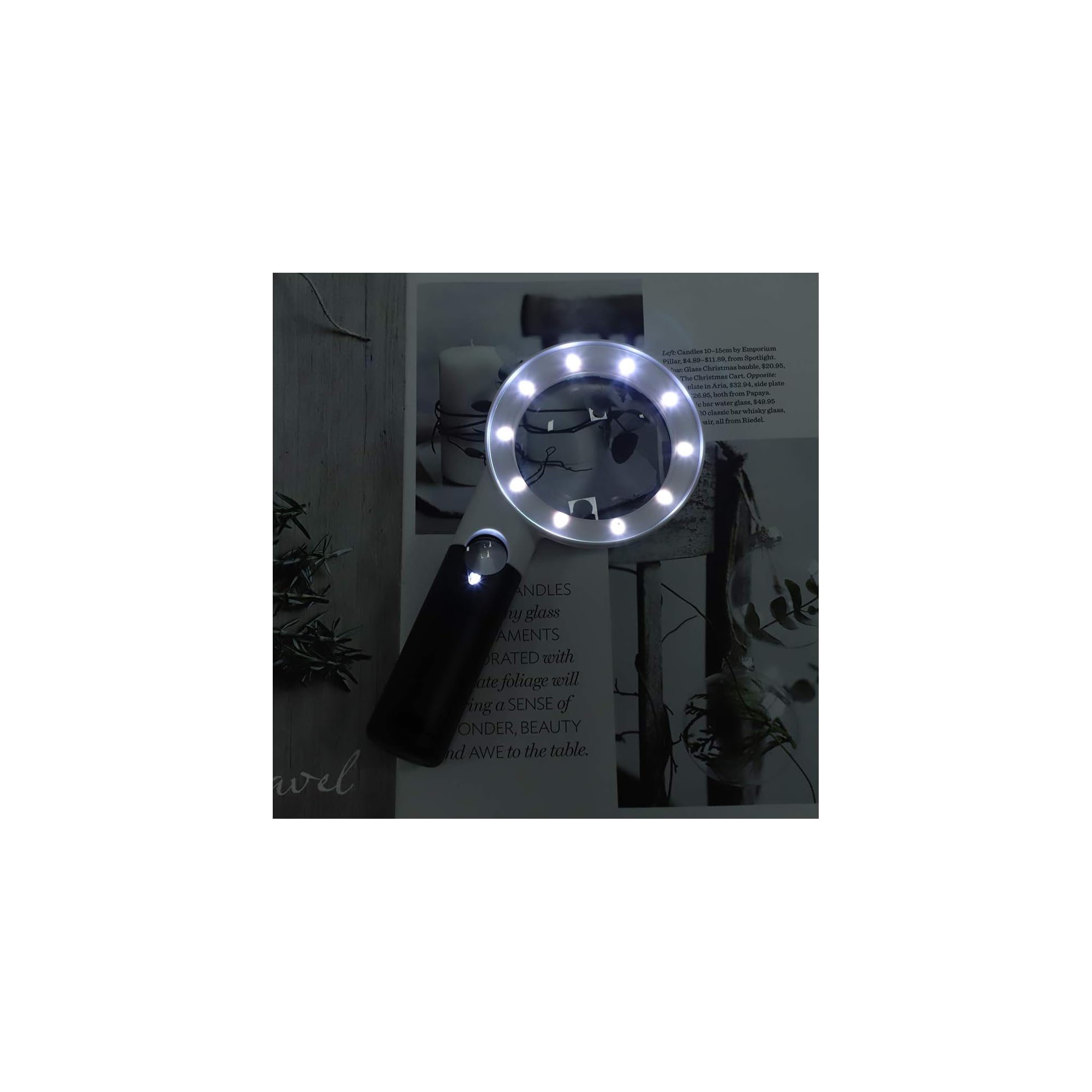 Eine Handlupe mit hellen LEDs beleuchtet eine bedruckte Magazineseite mit Text und Fotos.